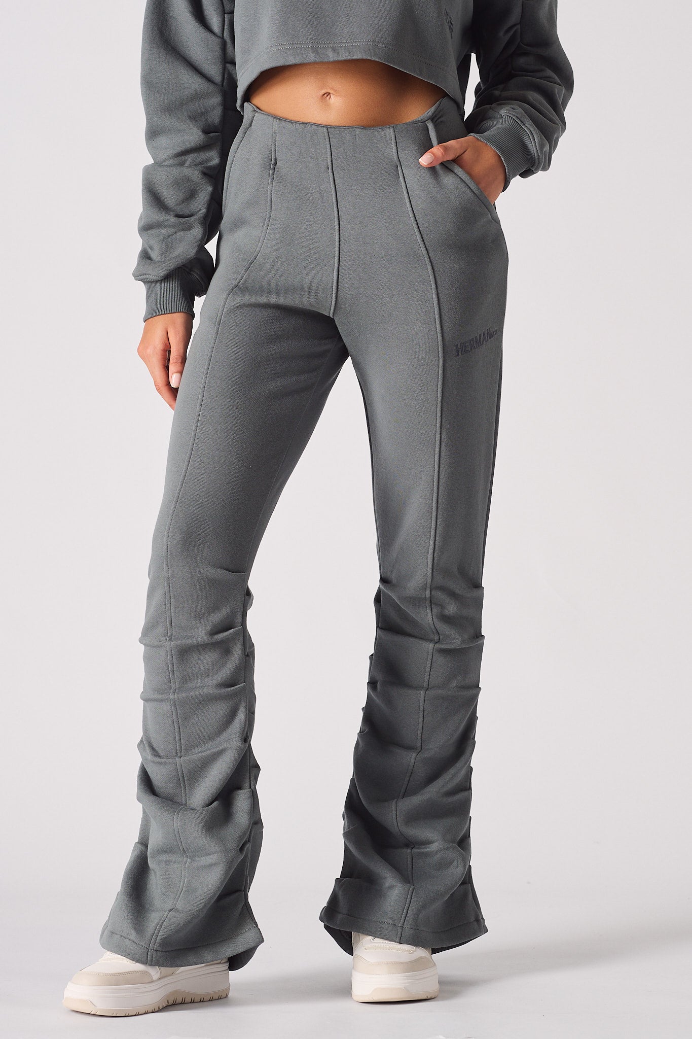 Detailed view of the flared hem and ruched stitching on grey joggers