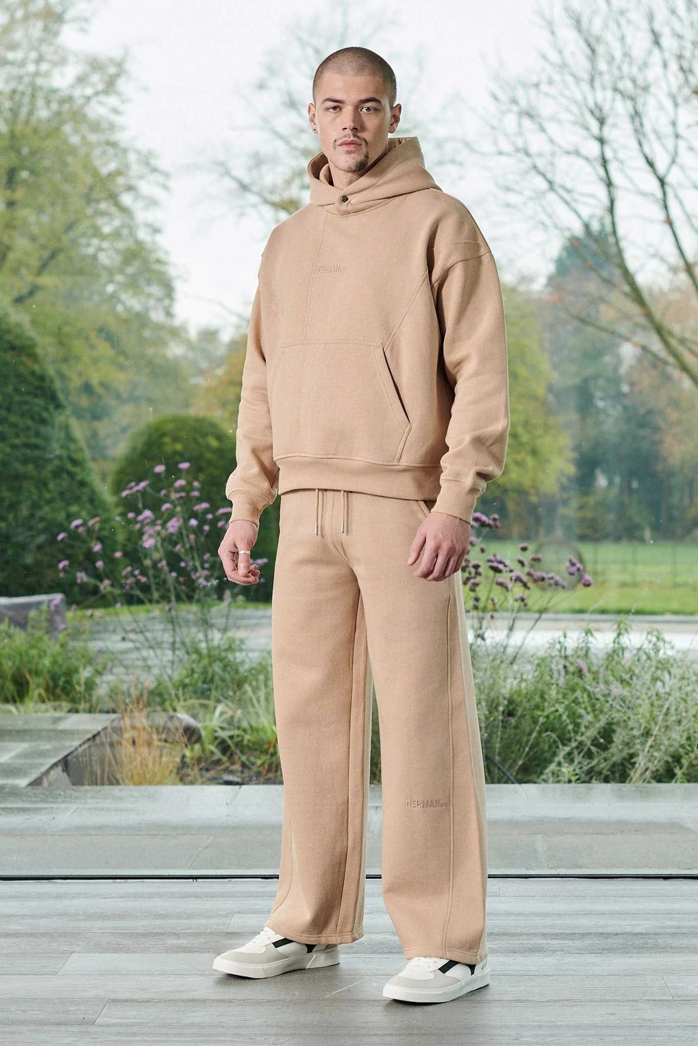 A model wearing beige joggers for men with a matching hoodie