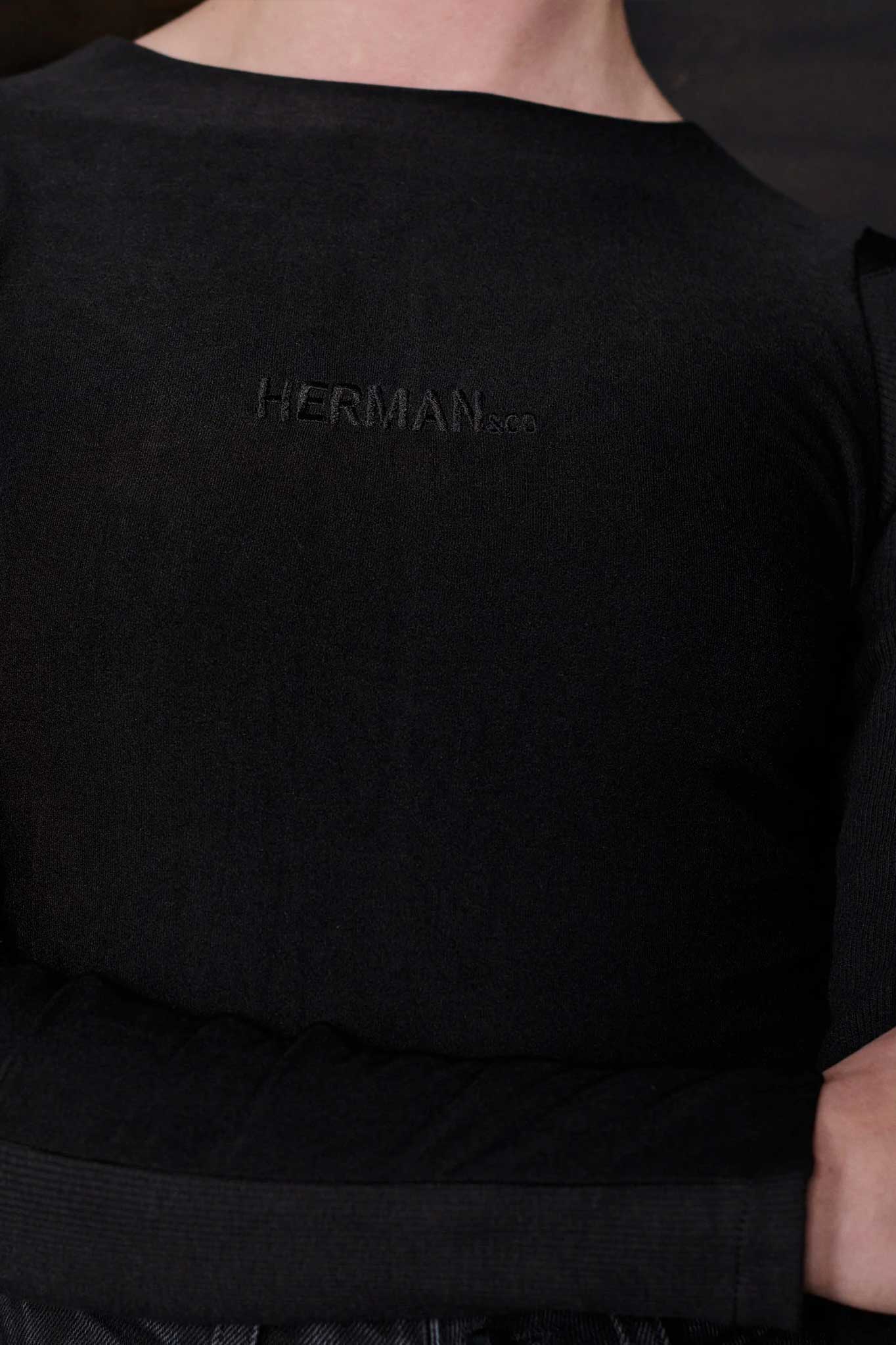 Close-up of the tonal embroidered logo on the black bodysuit.