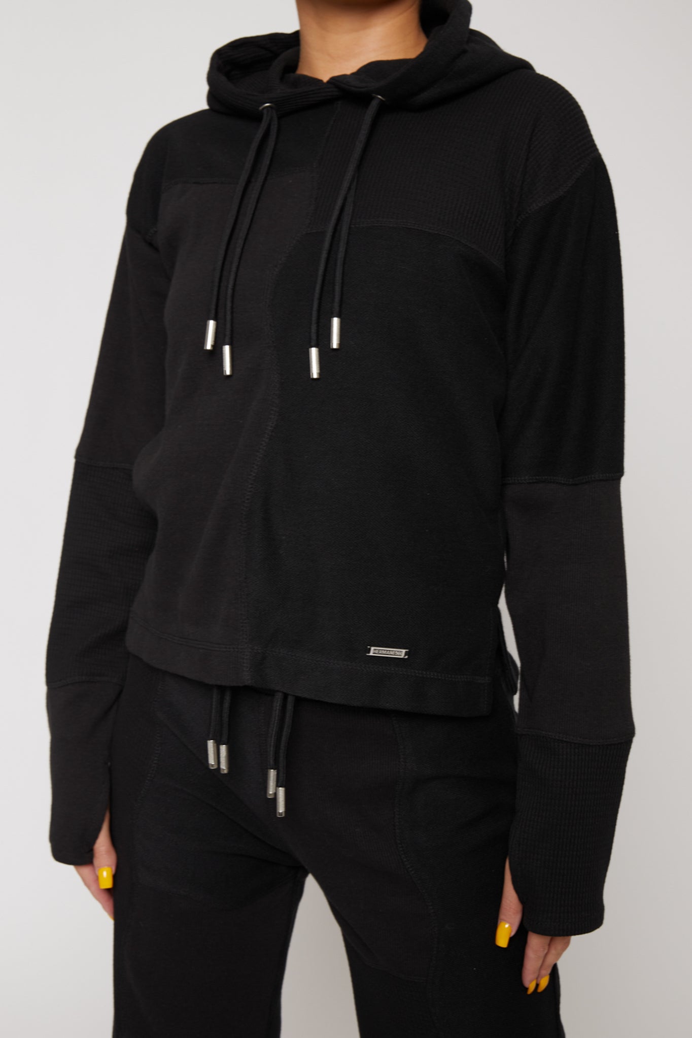 Close up view of the front pocket and overlock stitching on black hoodie