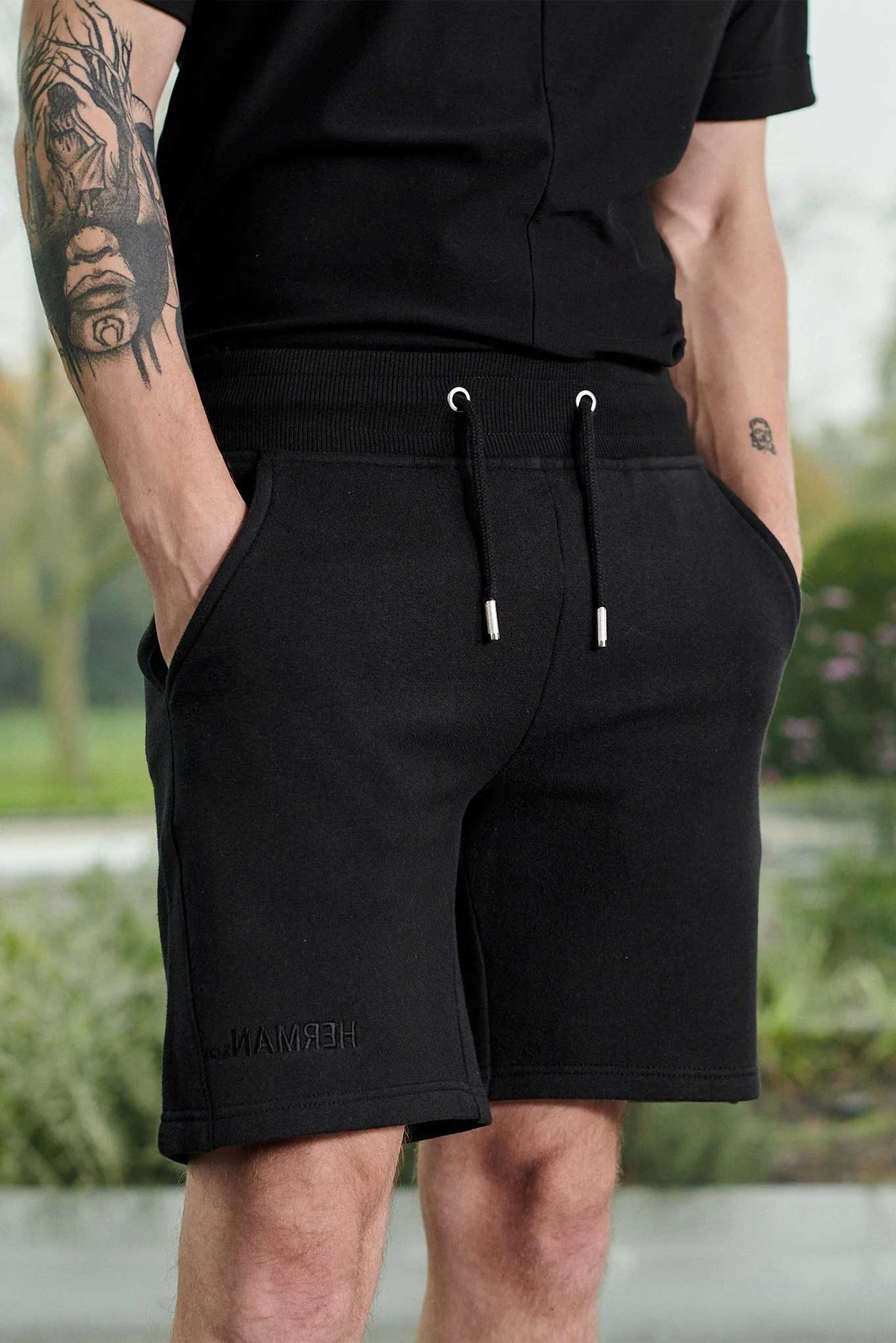 Close up mid section view of men's hands in pockets of black fleece shorts