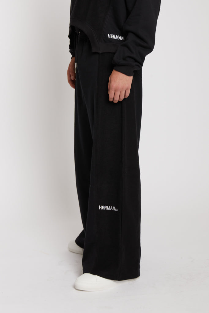 Close up side view of the Herman logo on black wide leg joggers mens