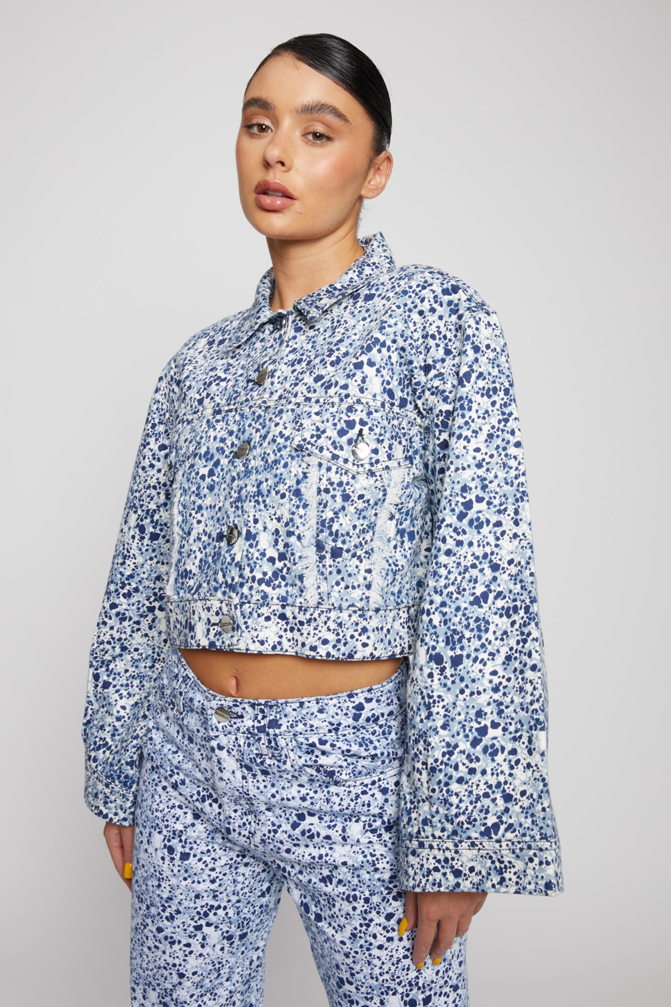 A model wearing the blue and white marble print denim jacket.