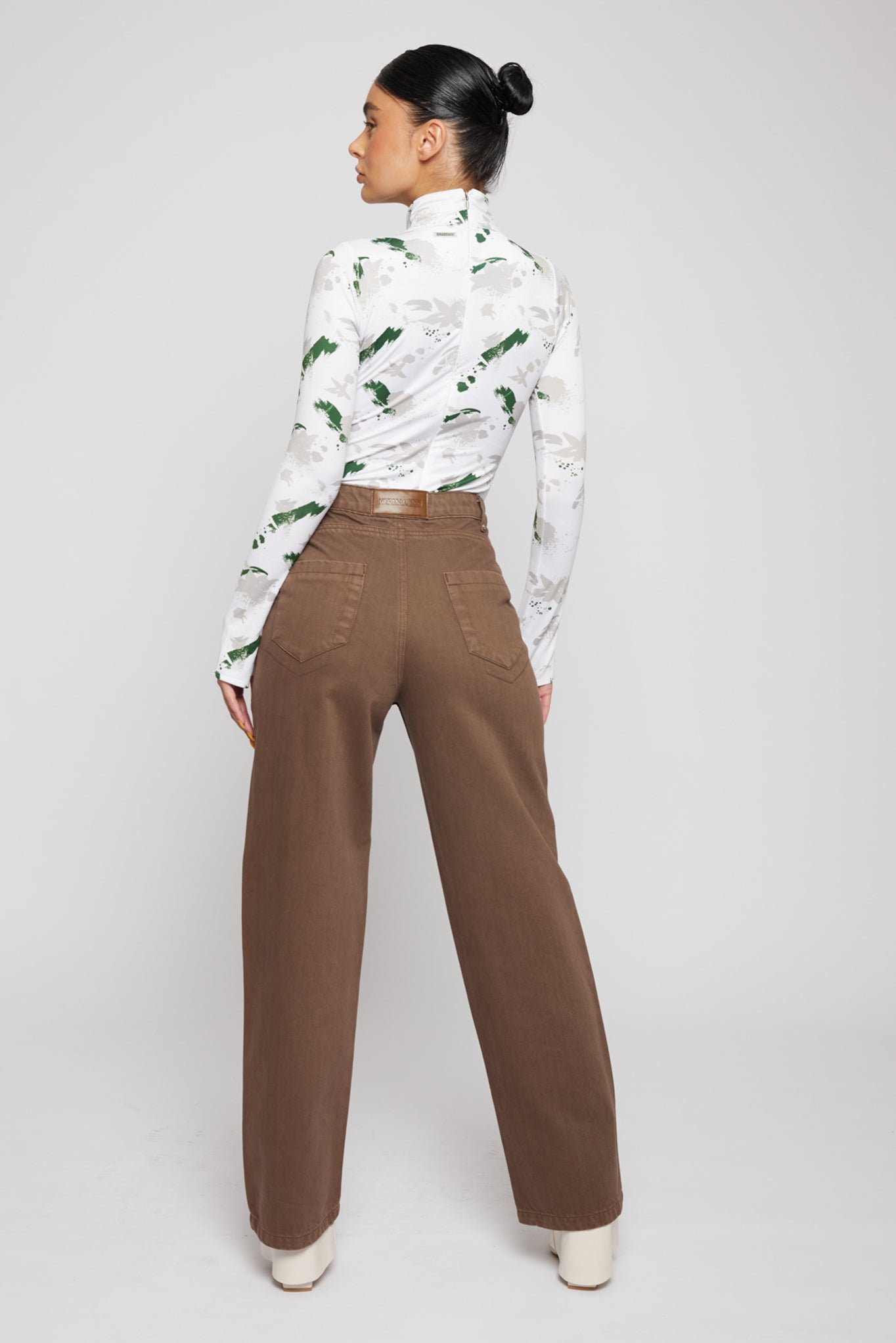 Angled back view of a model wearing the brown baggy jeans for women.