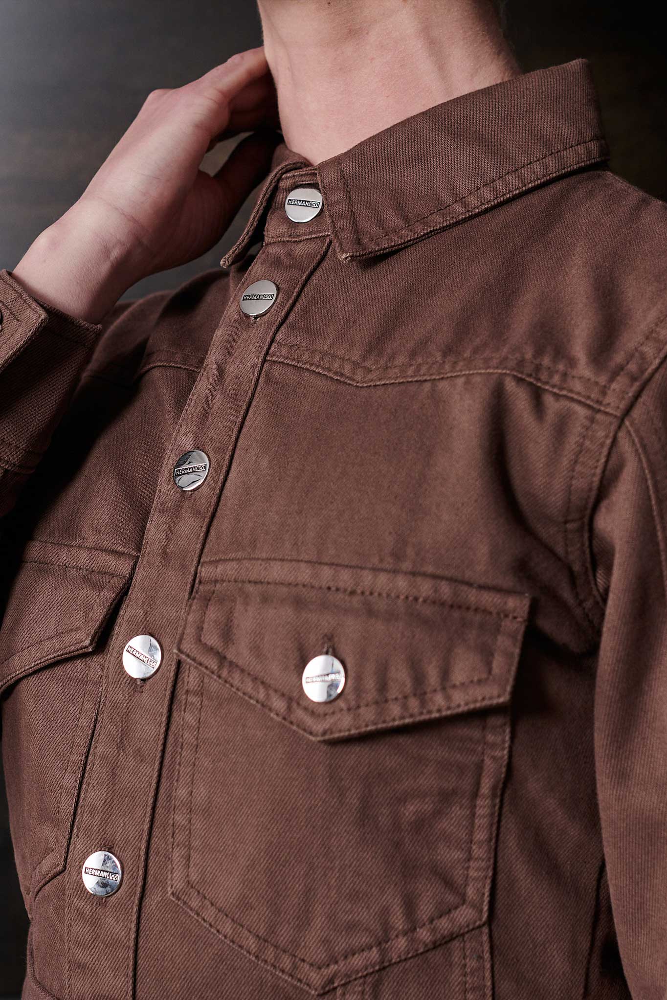 Close-up of the silver branded buttons and chest pocket on the brown denim dress