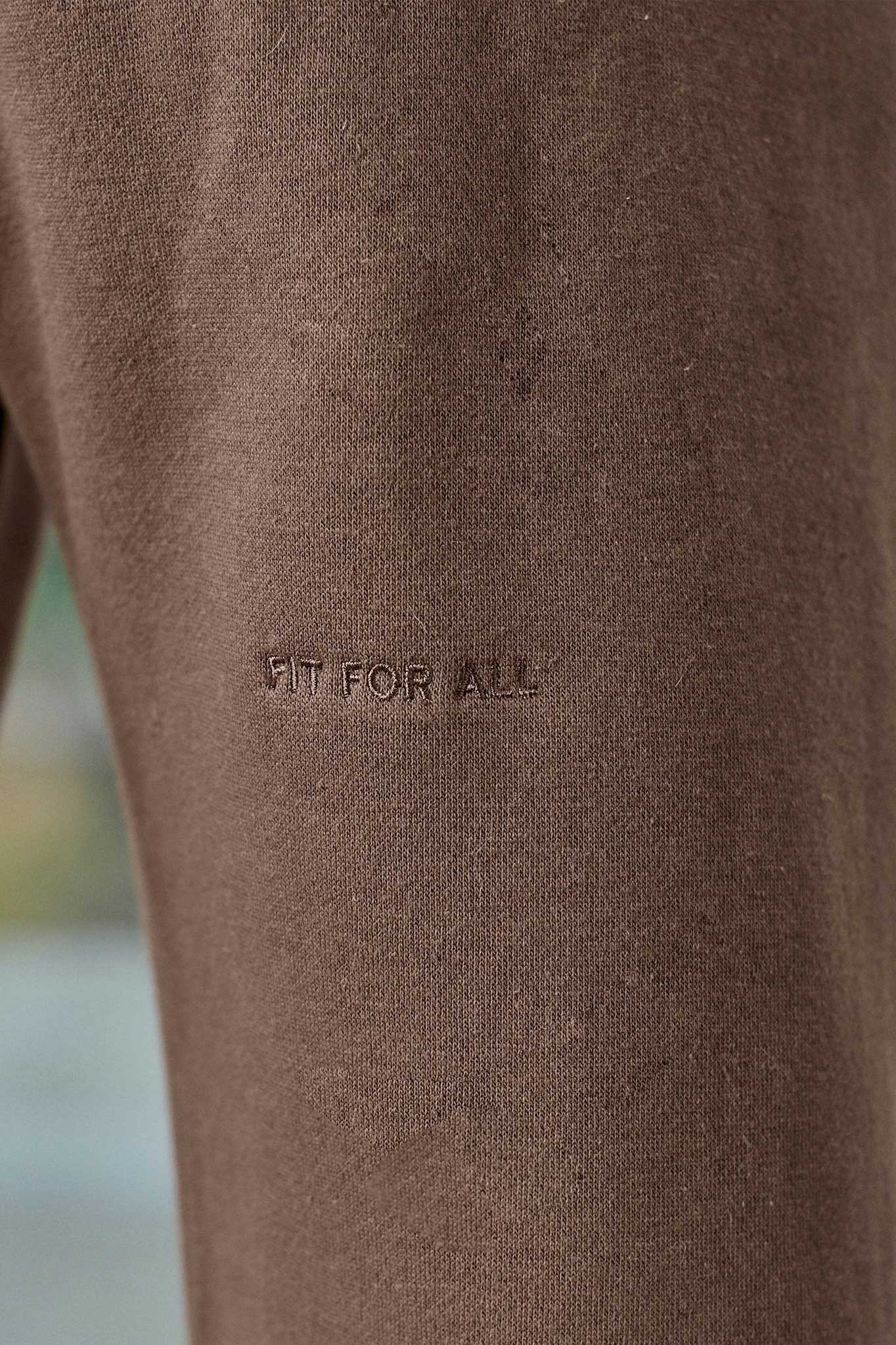 Close-up of the 'Fit For All' tonal embroidery on the men's brown joggers