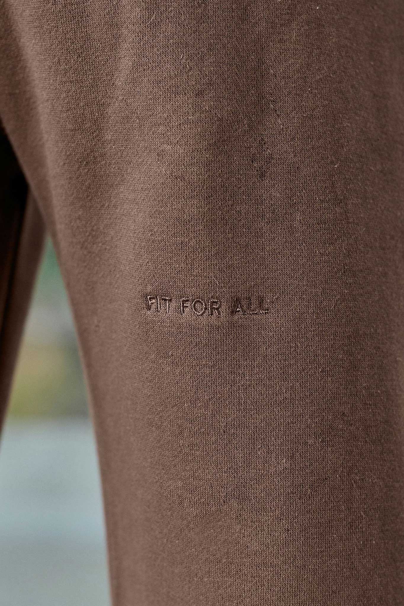 Close-up of the tonal 'Fit For All' embroidery on the brown joggers
