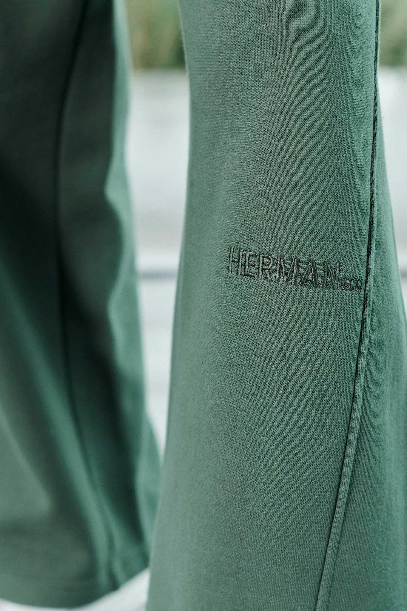 Detailed view of the tonal logo embroidery on the dark green joggers for men.