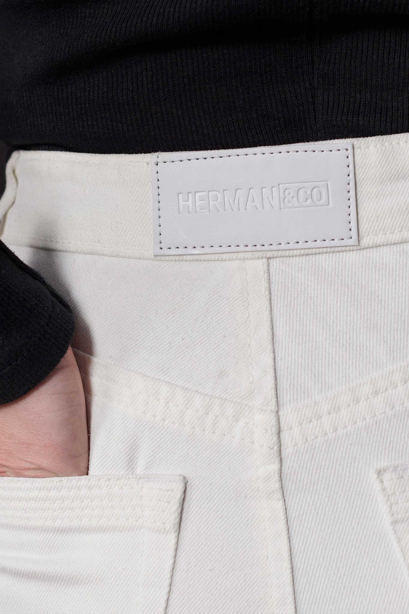 Close-up of the back waistband and logo patch on the distressed jeans for women.