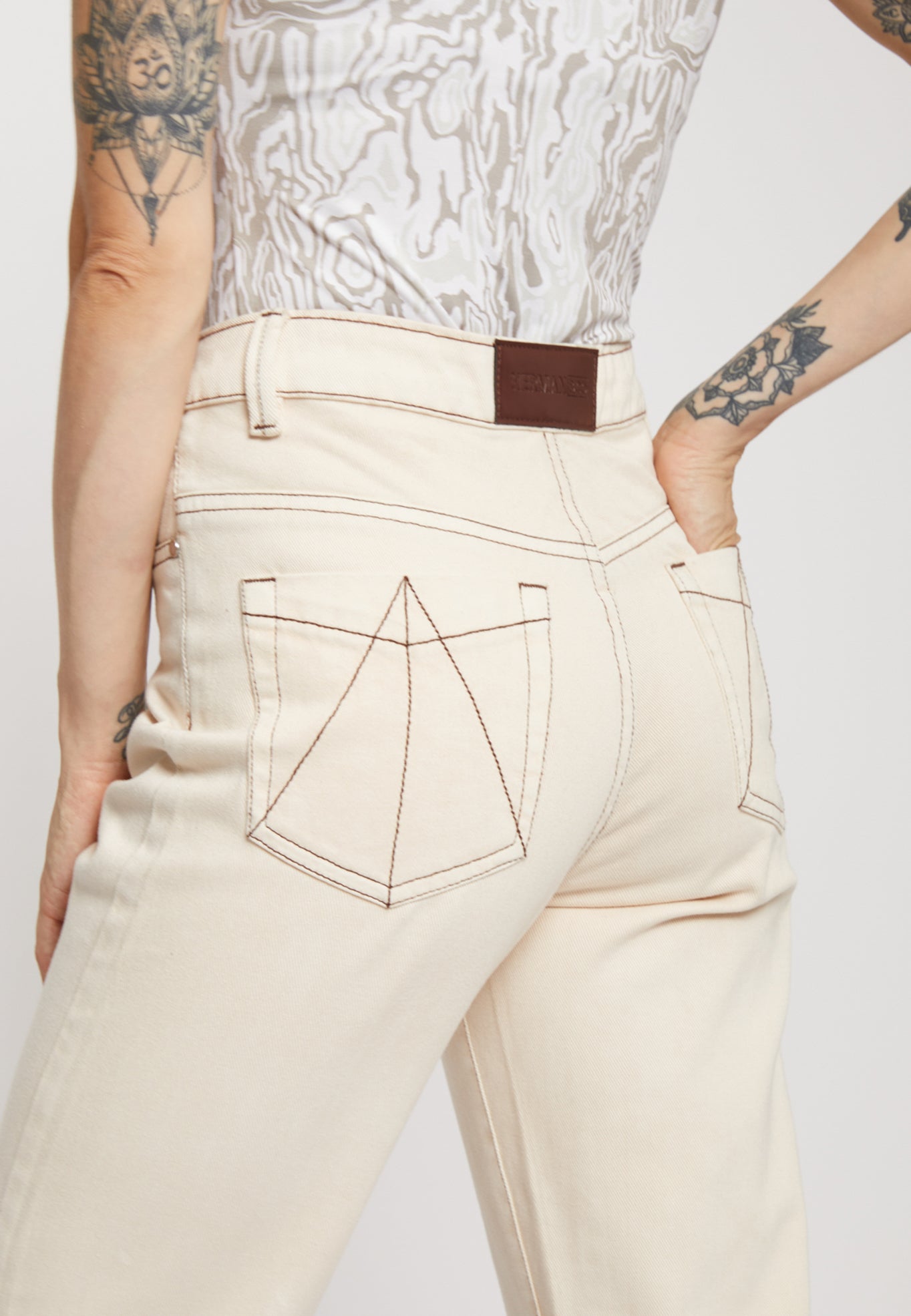Close-up of the brown contrast stitching on the back pocket of the ecru jeans