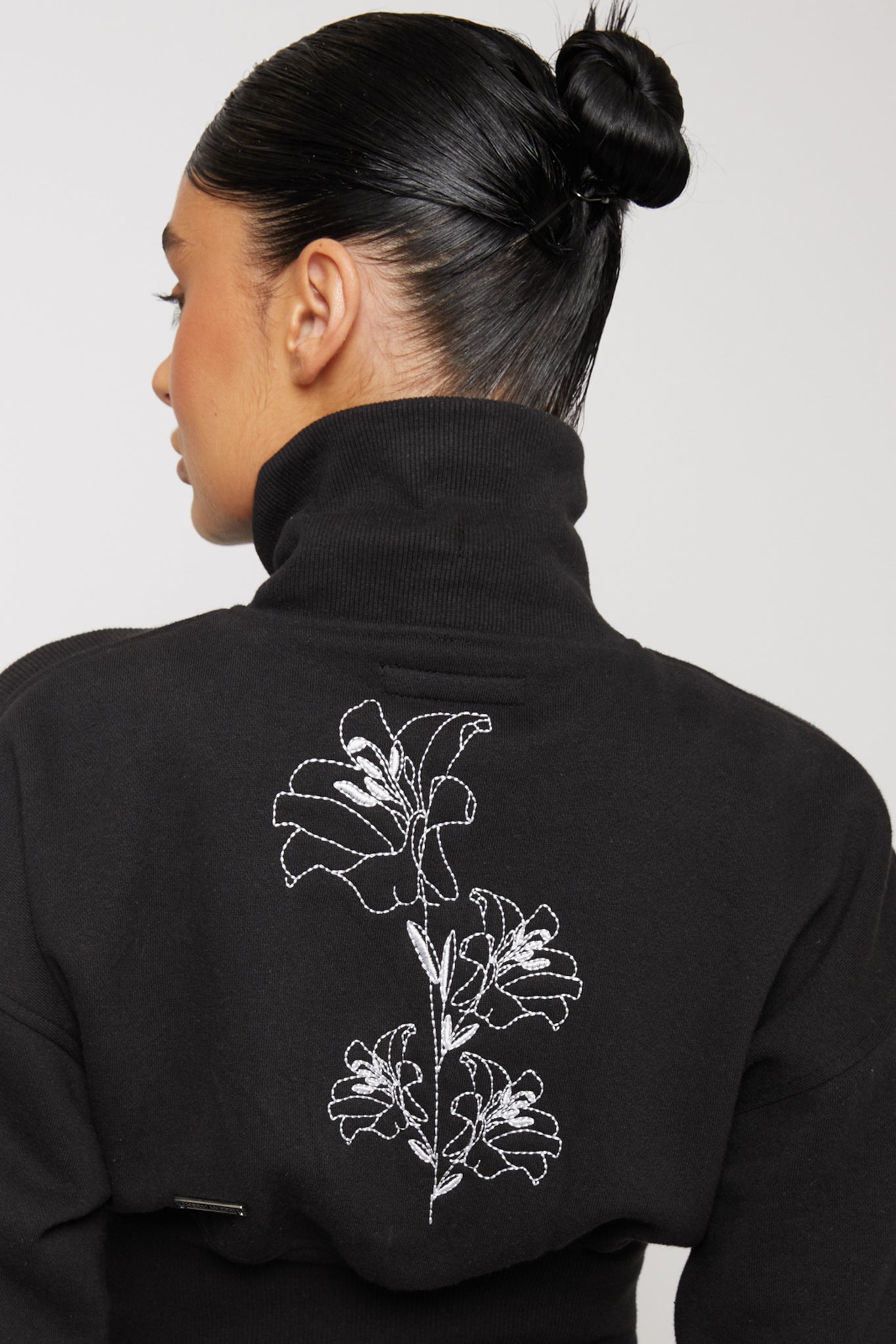 Close up detail of the white floral embroidery on the back of black sweatshirt