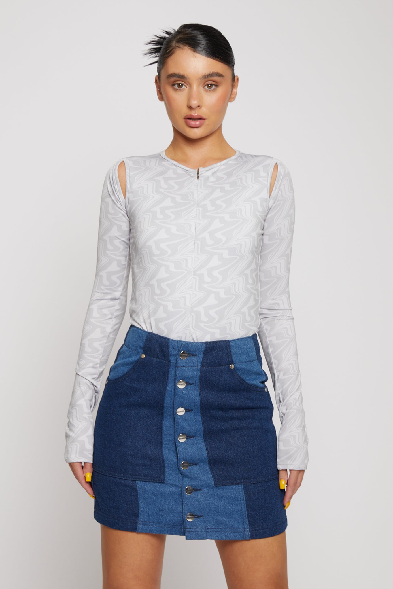 Front view of a model in the light grey cut-out shoulder bodysuit.