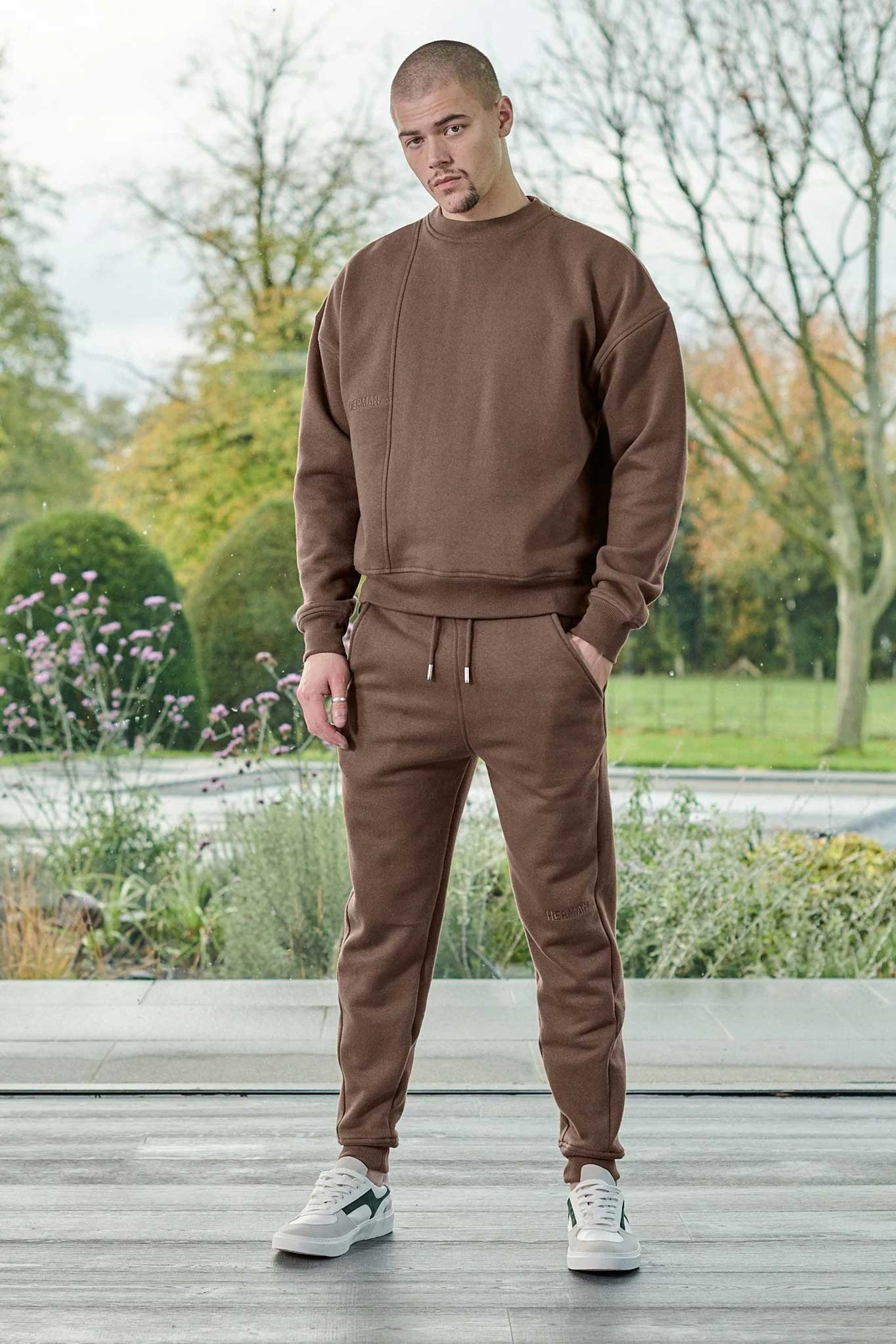 A model wearing the men's brown tapered jogger as part of a matching tracksuit set.