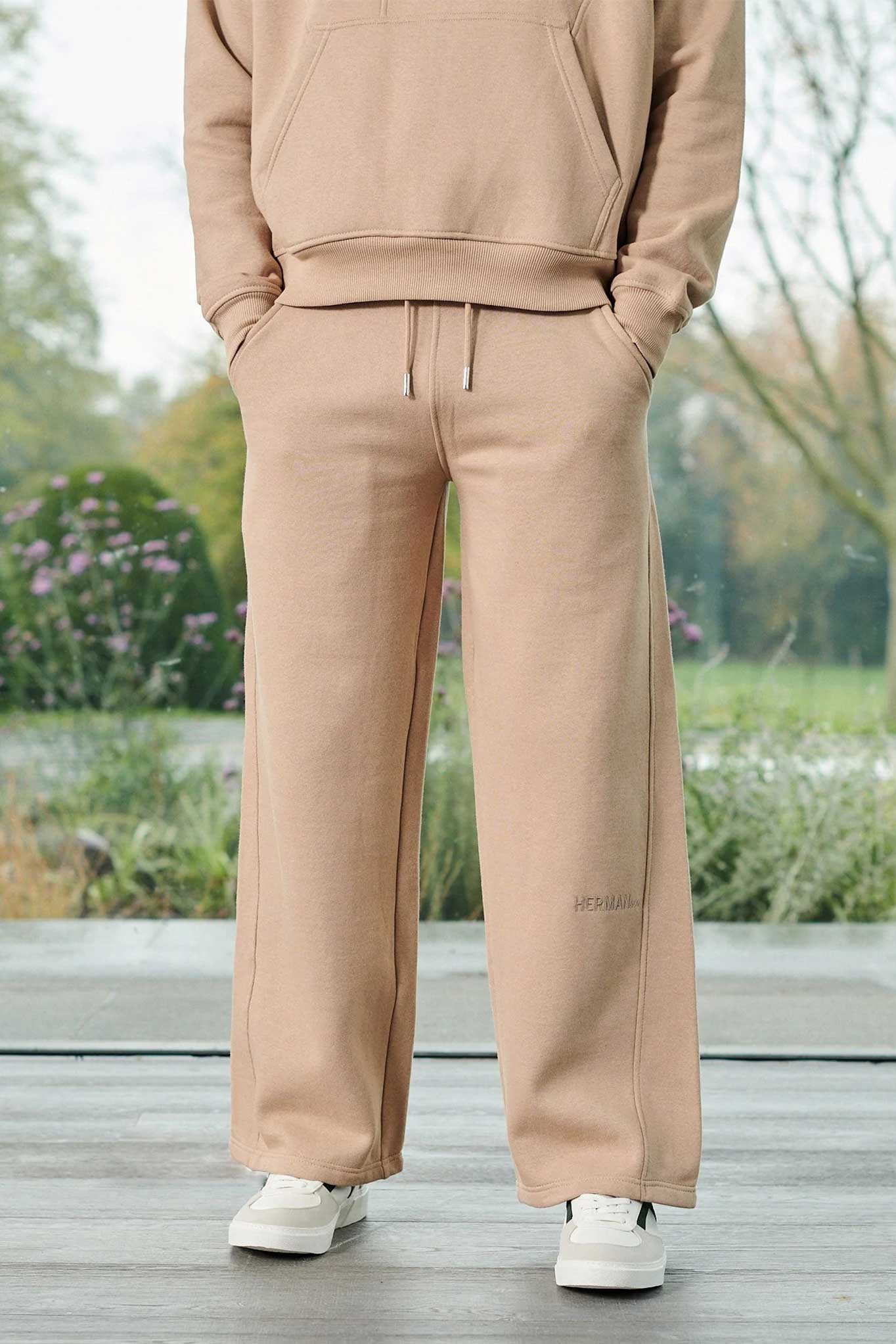 Close-up of the men's beige wide-leg joggers with embroidered logo detail