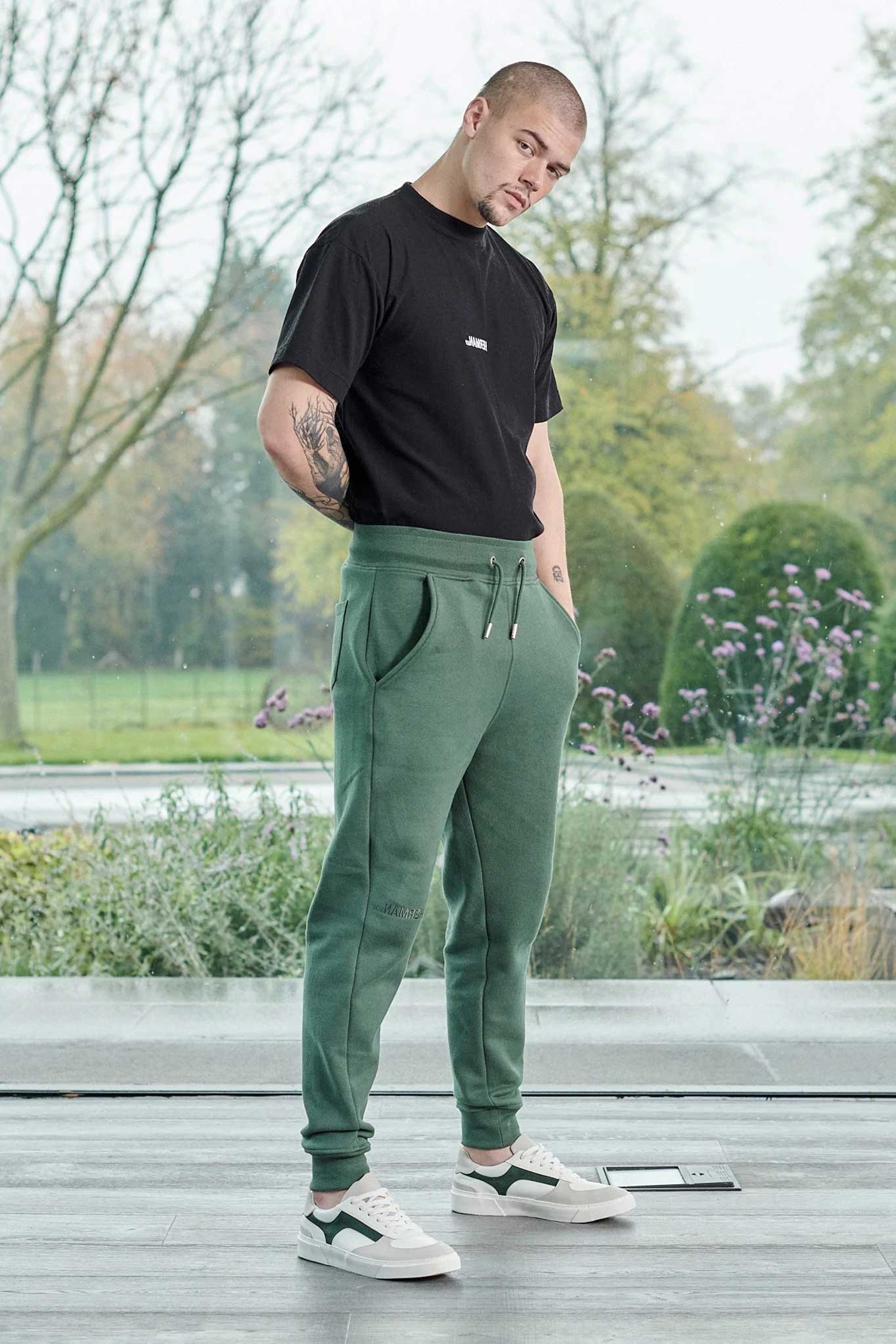 Front view of model wearing mens dark green joggers with a tapered fit