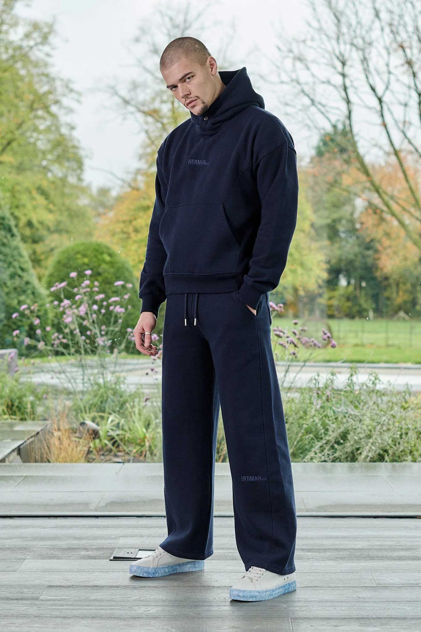 A model wearing the men's navy blue joggers with a matching hoodie.