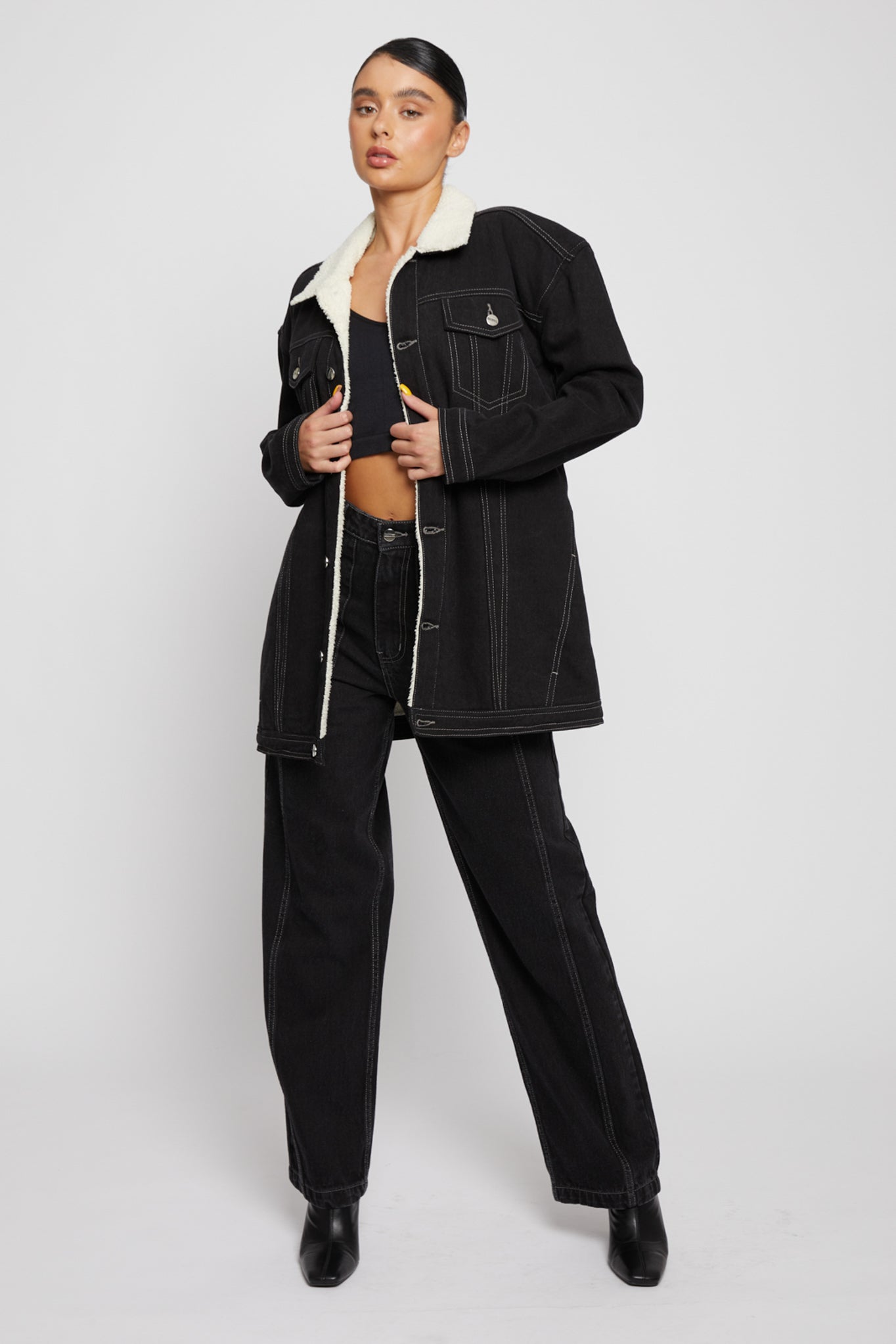 Full view of a model in an oversized black shearling denim jacket.