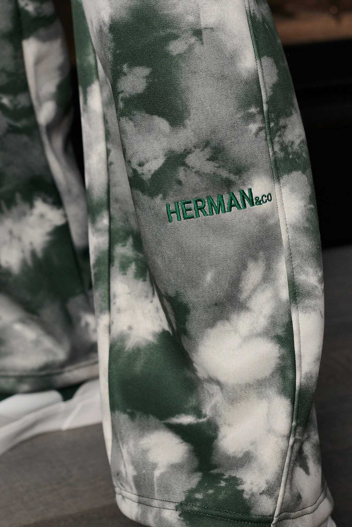 Close-up of the embroidered logo detail on the tie-dye oversized joggers.