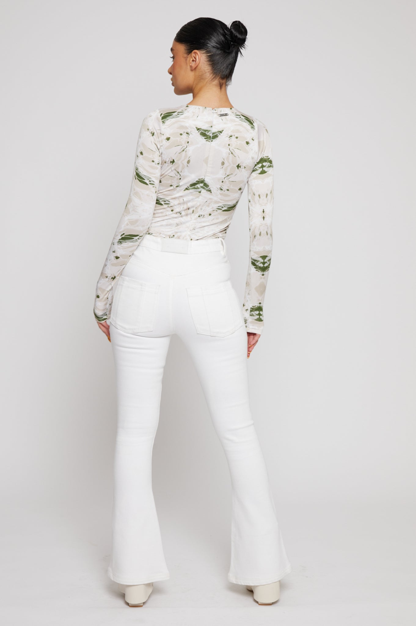 Back view of a model wearing the white high-waisted flared jeans.