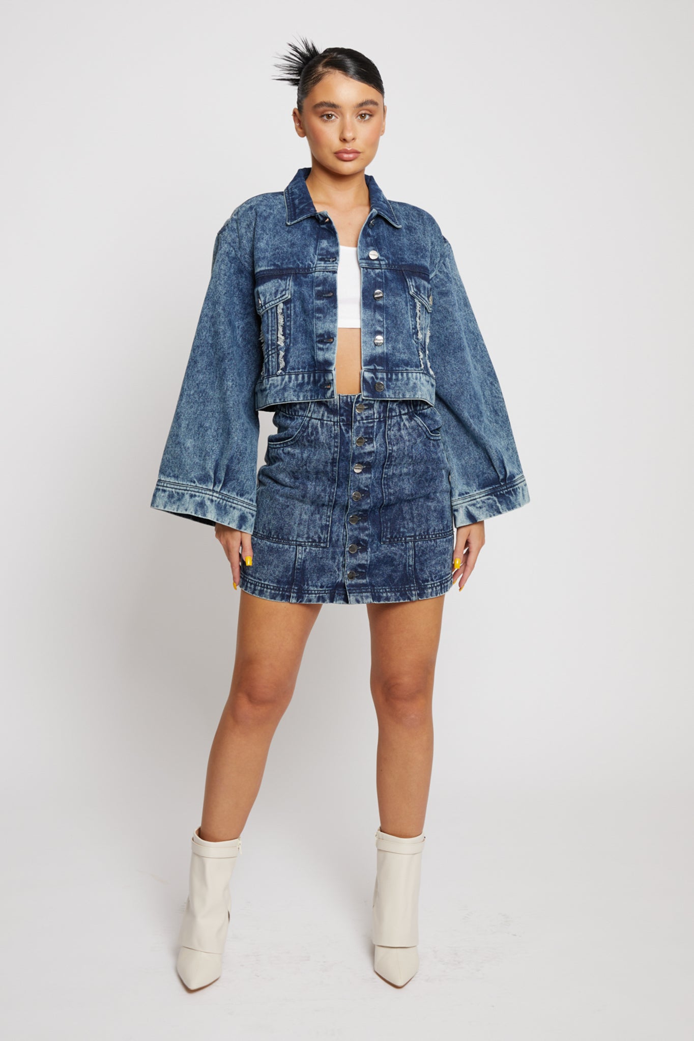 A model wearing the women's acid wash cropped jacket with a matching skirt.