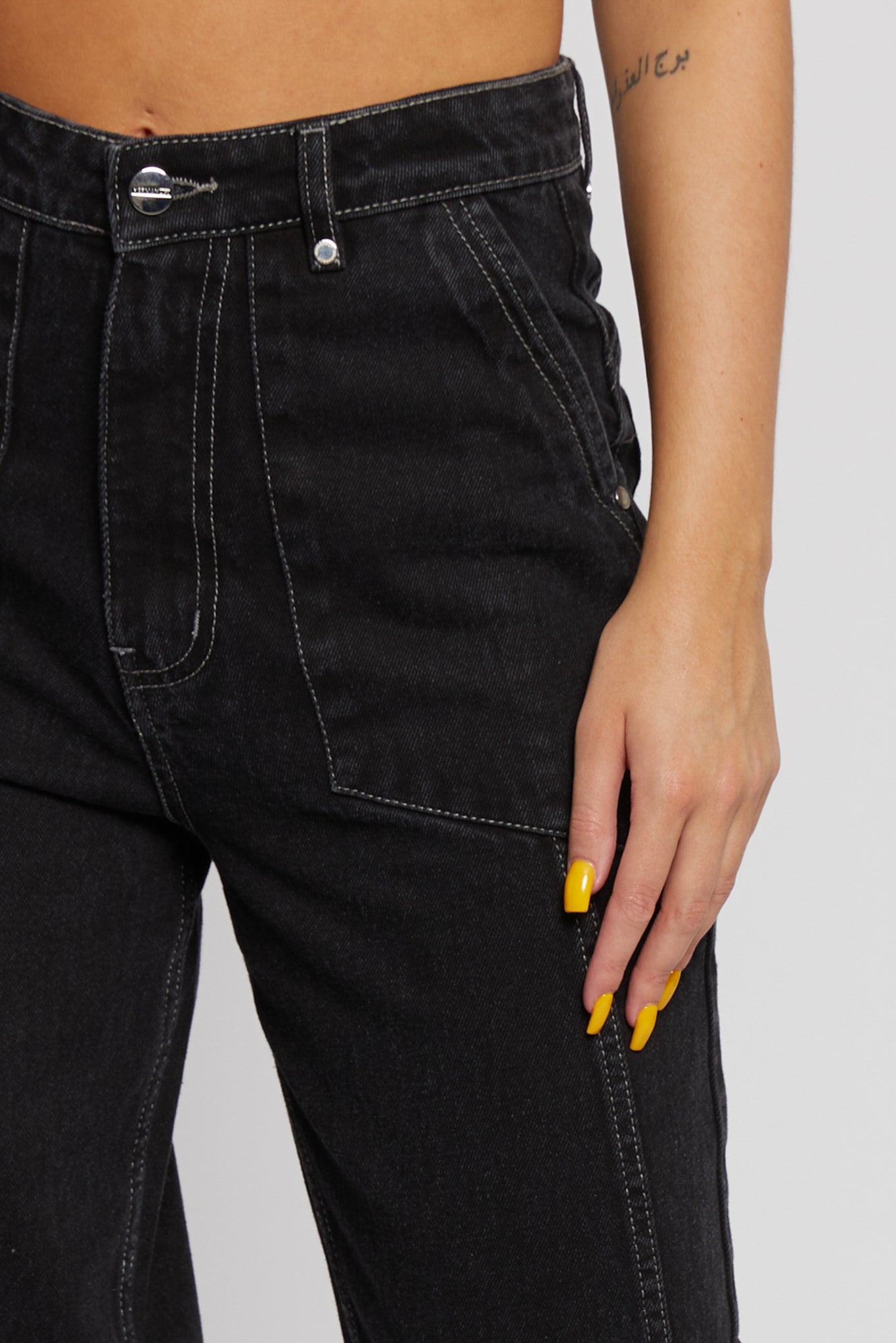 Close-up of the front pocket and high waist on the women's black wash jeans.