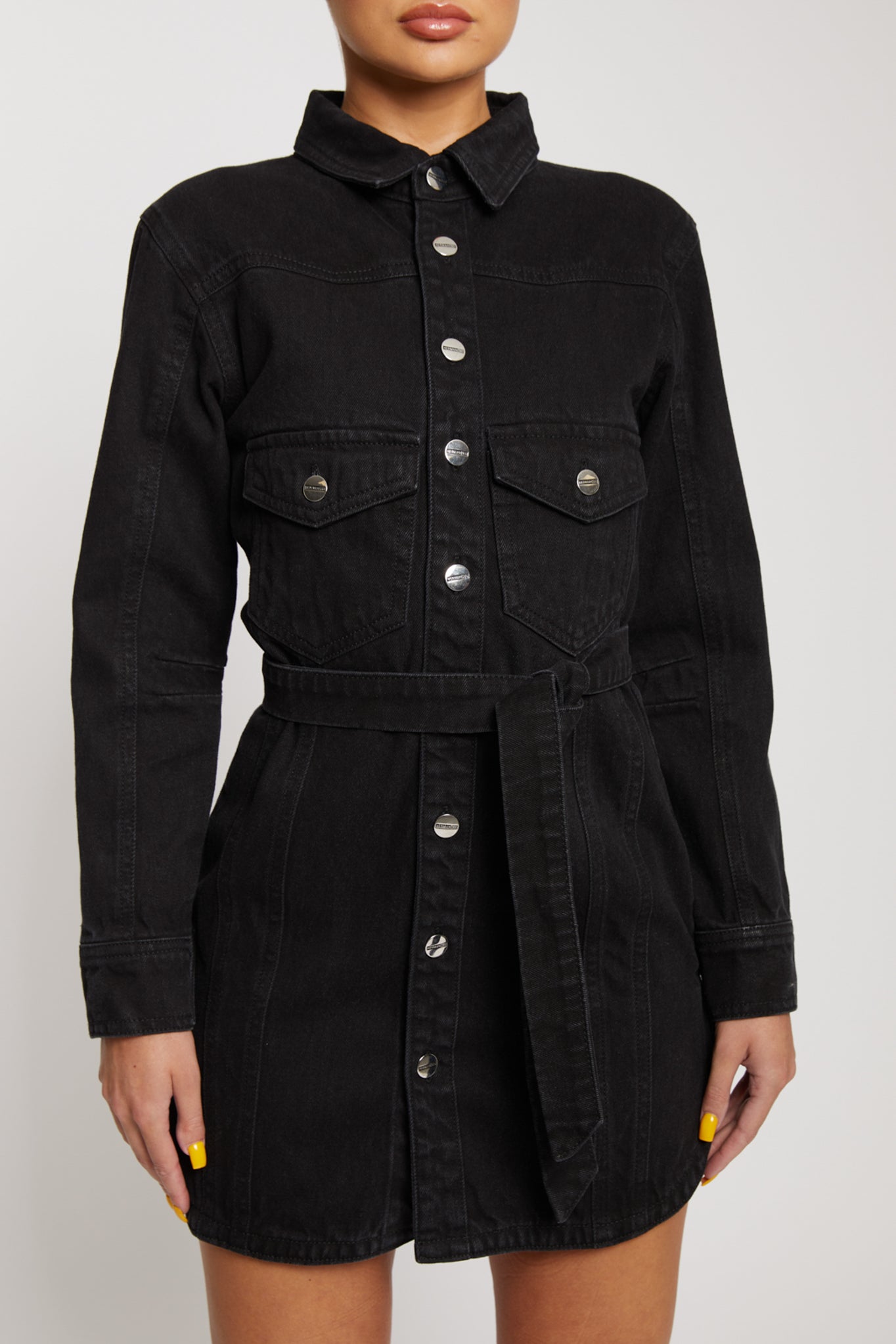 Close-up of the women's black washed denim dress, highlighting the chest pockets and tie belt