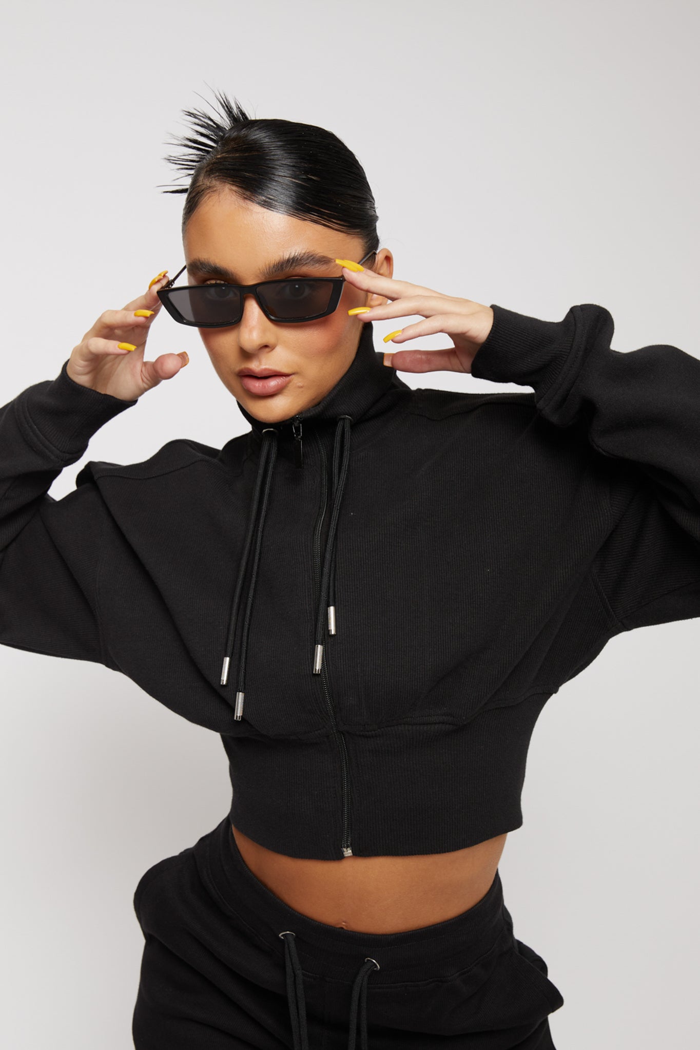 Model wearing a black zip neck sweatshirt women style with chest logo detail