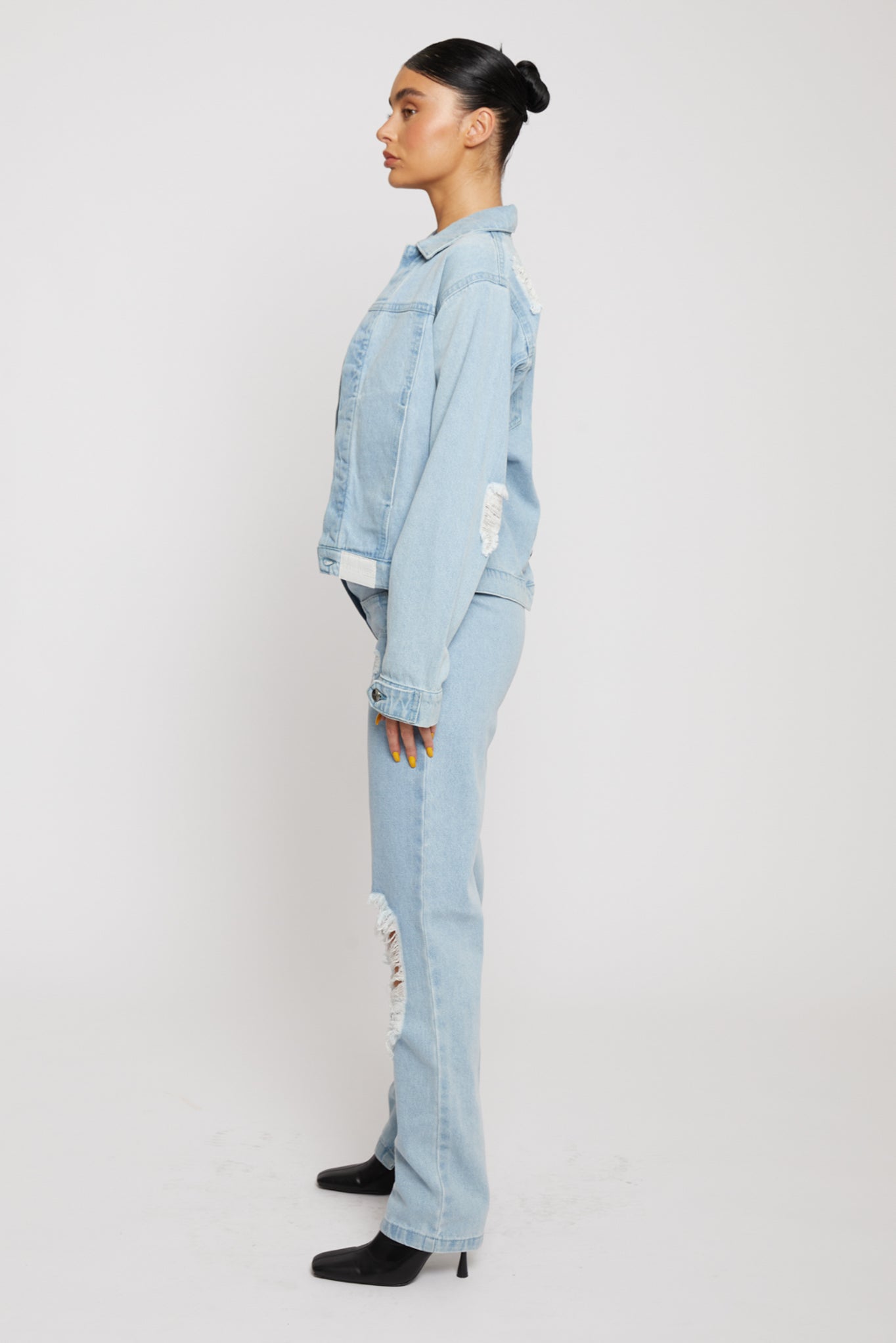 Side profile of a model wearing the women's distressed jean jacket.