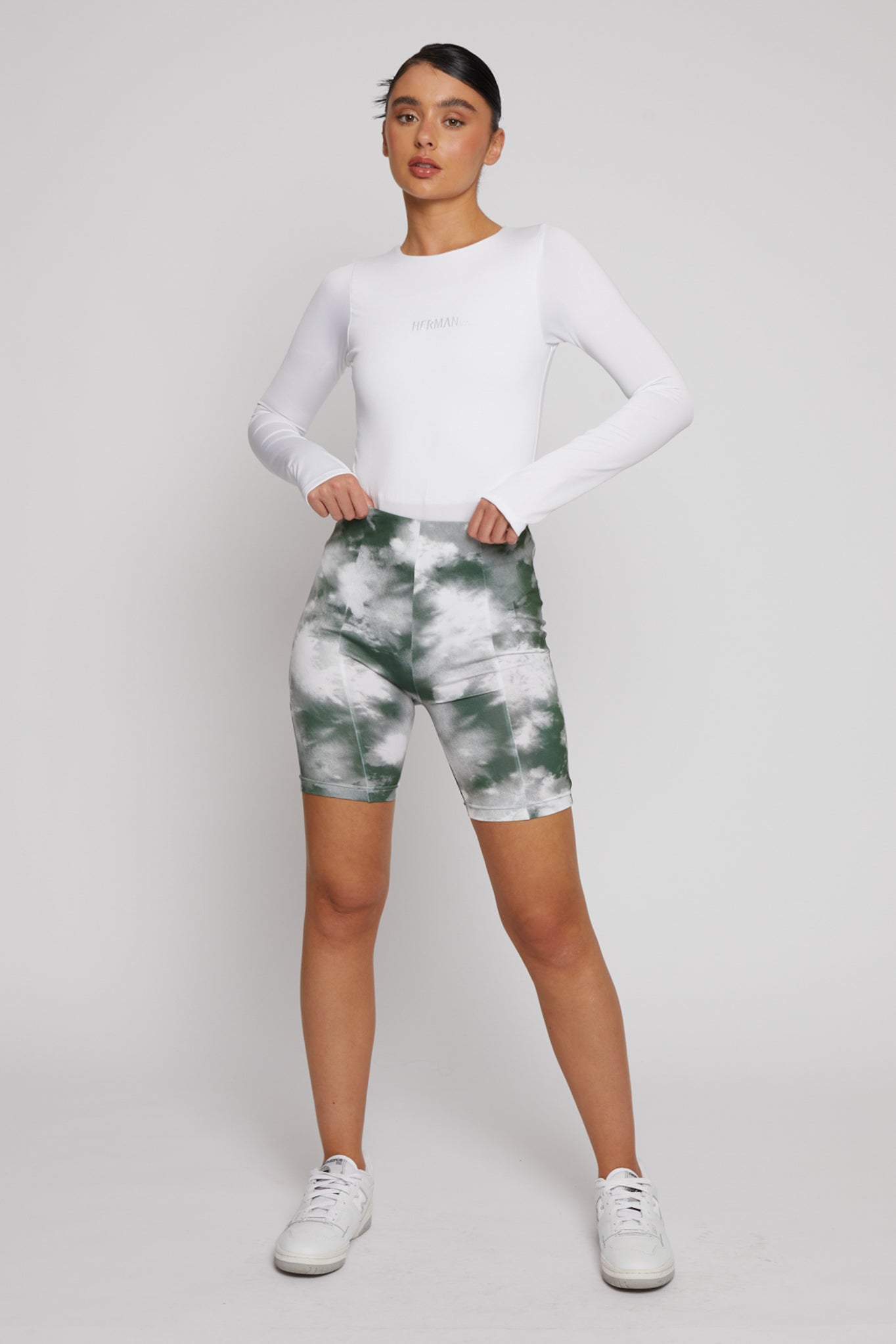 A model styled in the women's white long-sleeve bodysuit with shorts.