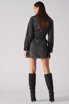Back view of a model wearing the acid wash denim dress, highlighting the belt and panel details