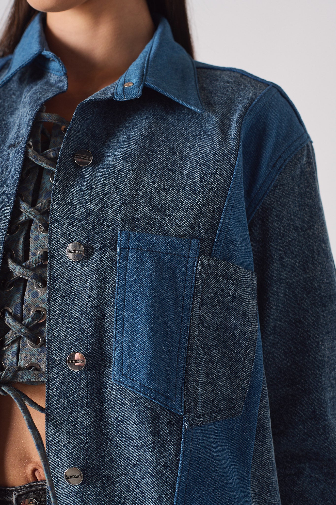 Close-up of the button-front detail on the acid wash denim shirt.