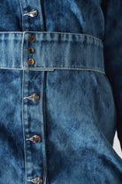 Close-up of the popper belt and branded buttons on the acid wash dress