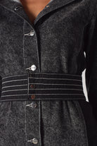 Detailed close-up of the white contrast stitching on the belt of the acid wash dress