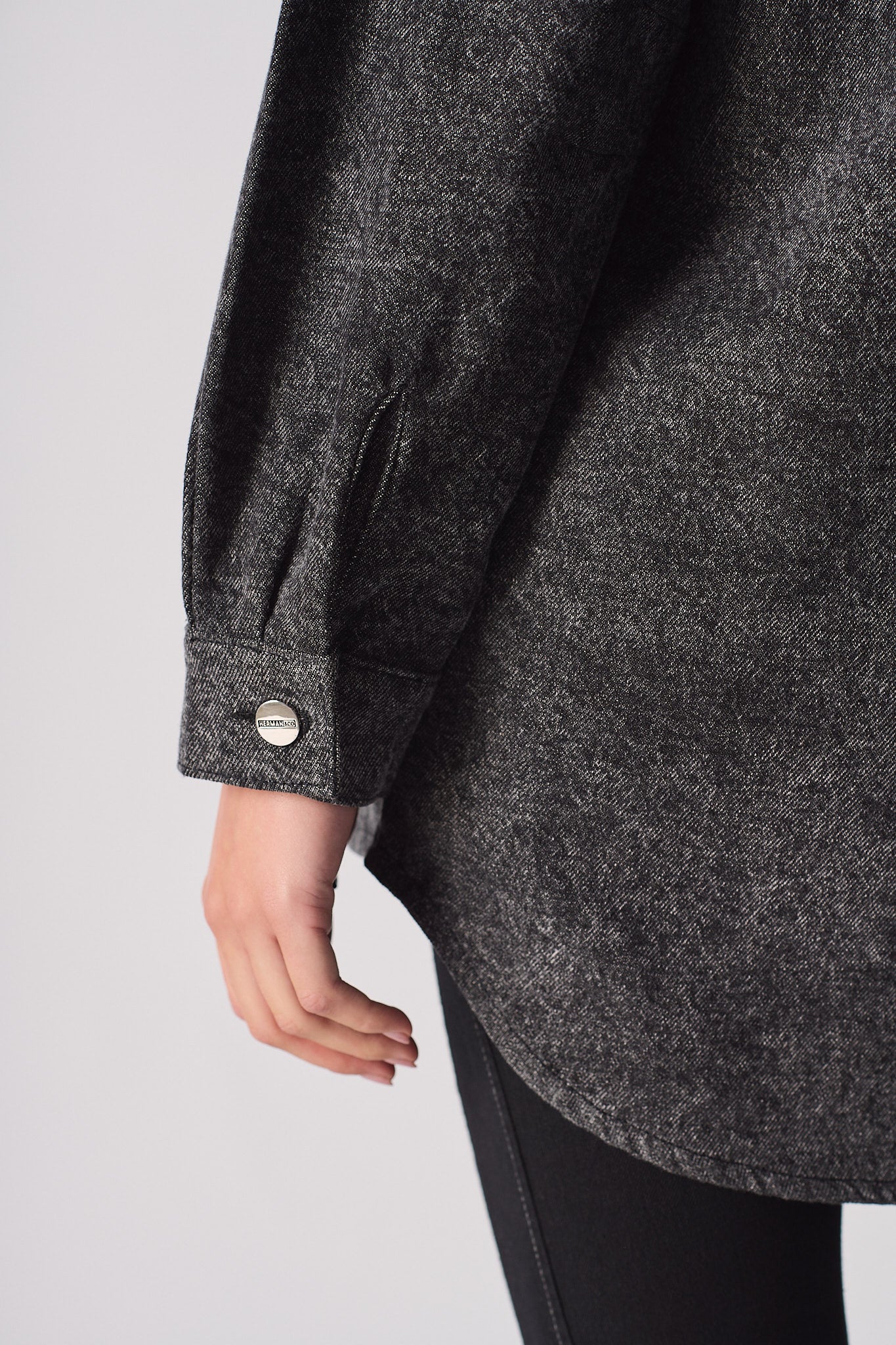 Close-up of the button cuff detail on the acid washed denim shirt.