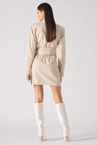 Back view of a model in the women's asymmetric shirt dress in beige.