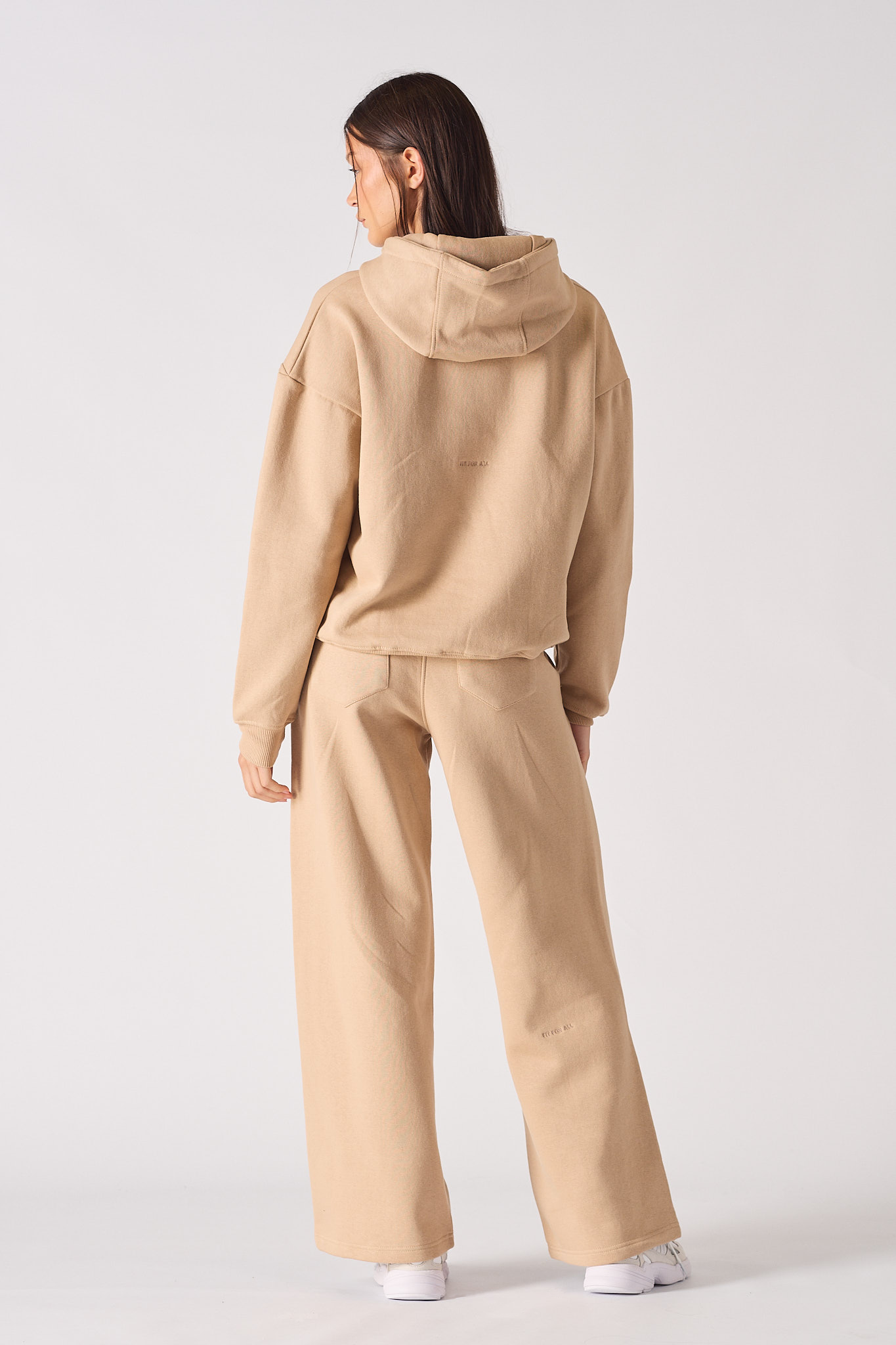 Rear full body view of model in a relaxed fit beige hoodie for women