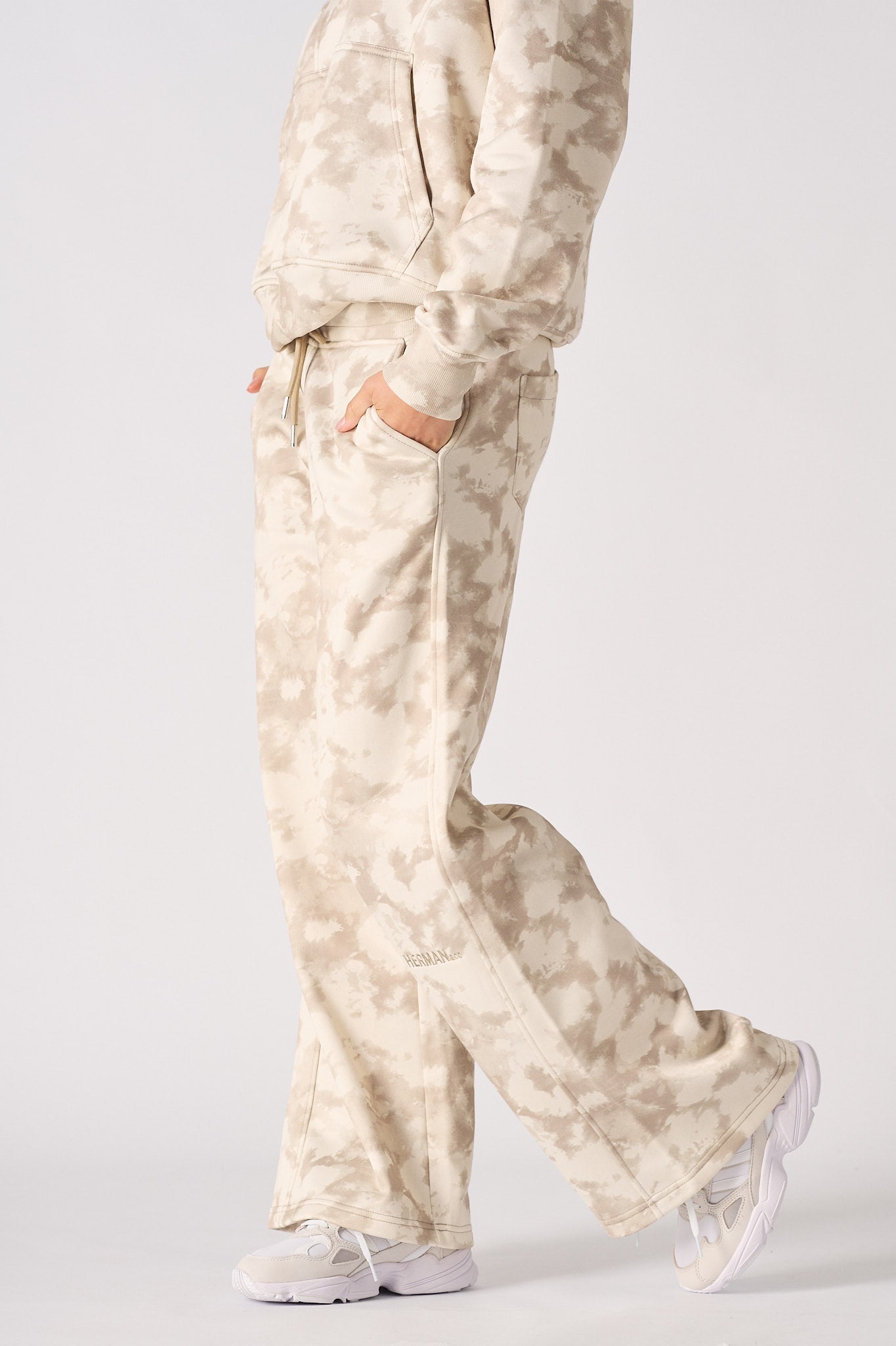 Close up side view of the pocket and wide leg fit on beige tie dye joggers