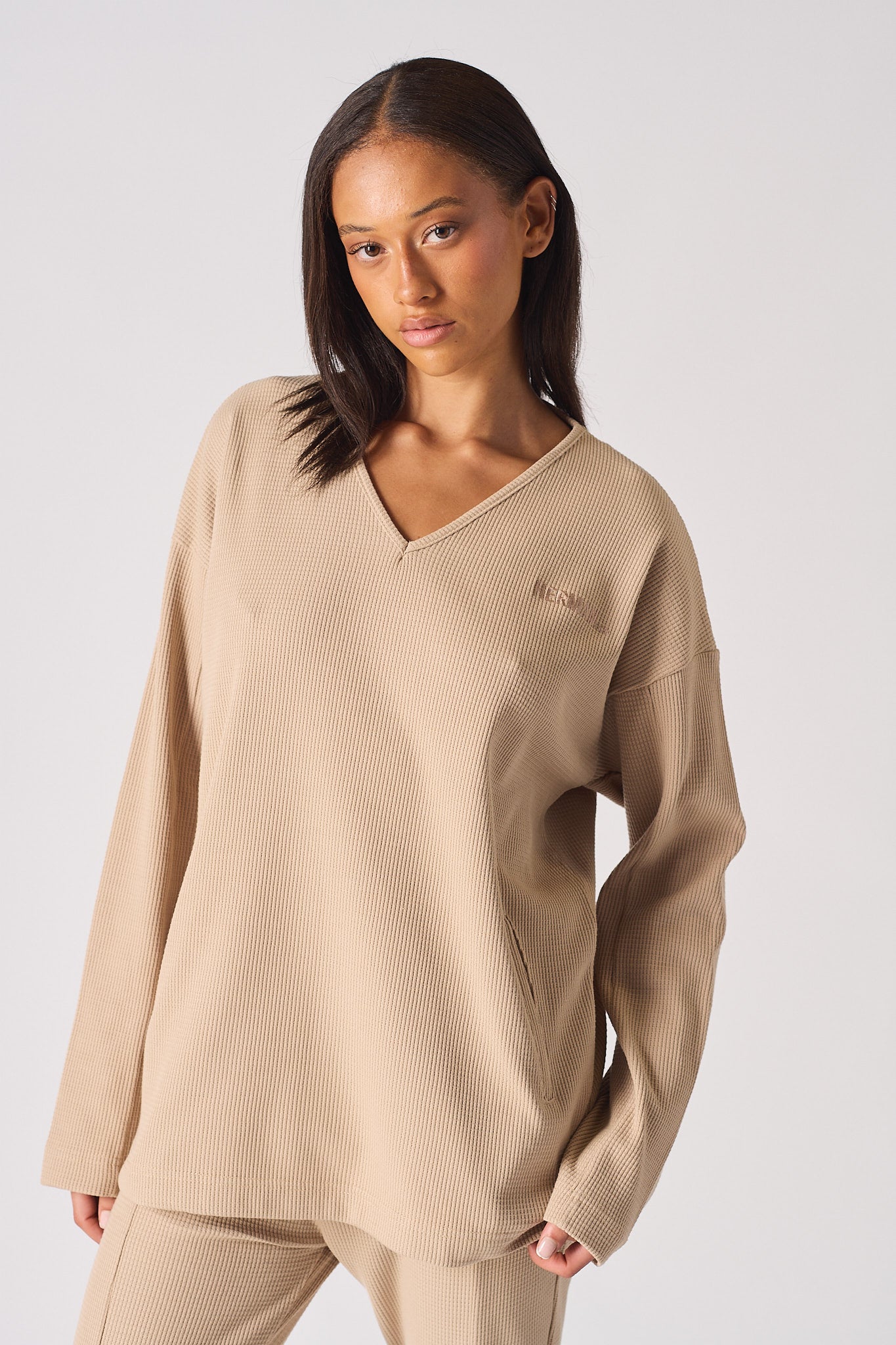 Model posing in a casual beige v neck jumper outfit for women