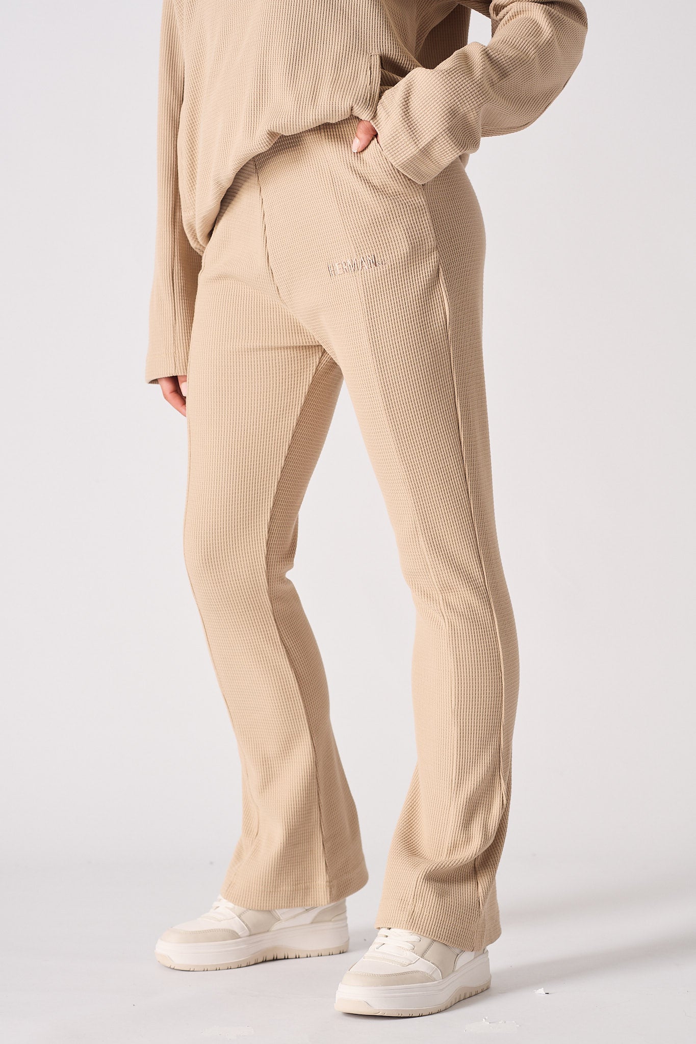 Side view of a model wearing beige waffle fit and flare joggers, showing the leg cut