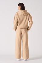 Back view of a model in the beige wide-leg joggers and hoodie set.