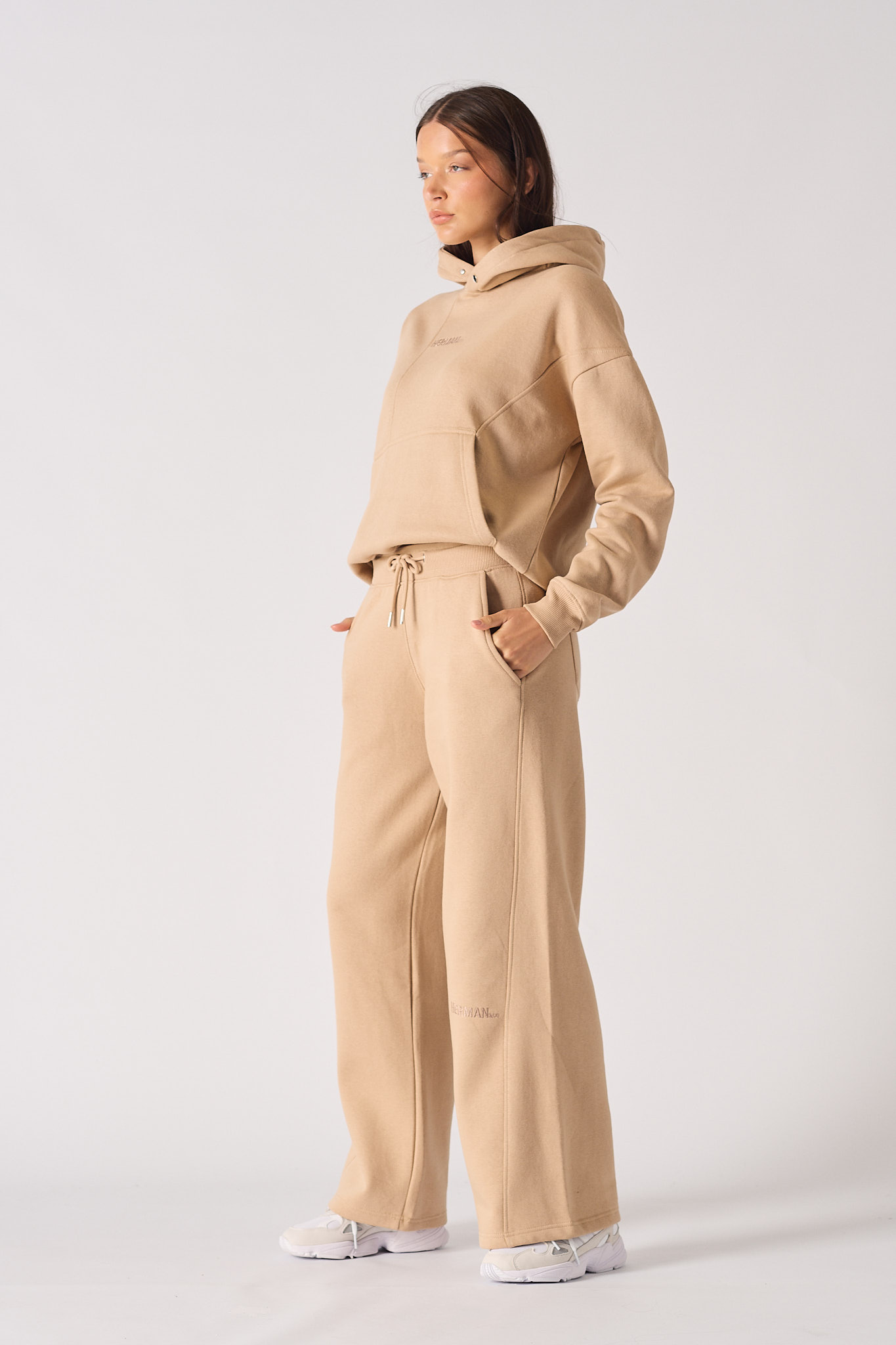 Side profile of a model wearing the beige wide-leg joggers for women.