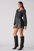 Side angle of a model wearing the black acid wash denim dress with high boots