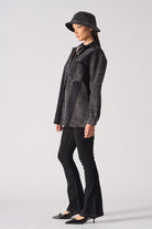 Side profile of a model showing the length of the black acid wash denim shirt.