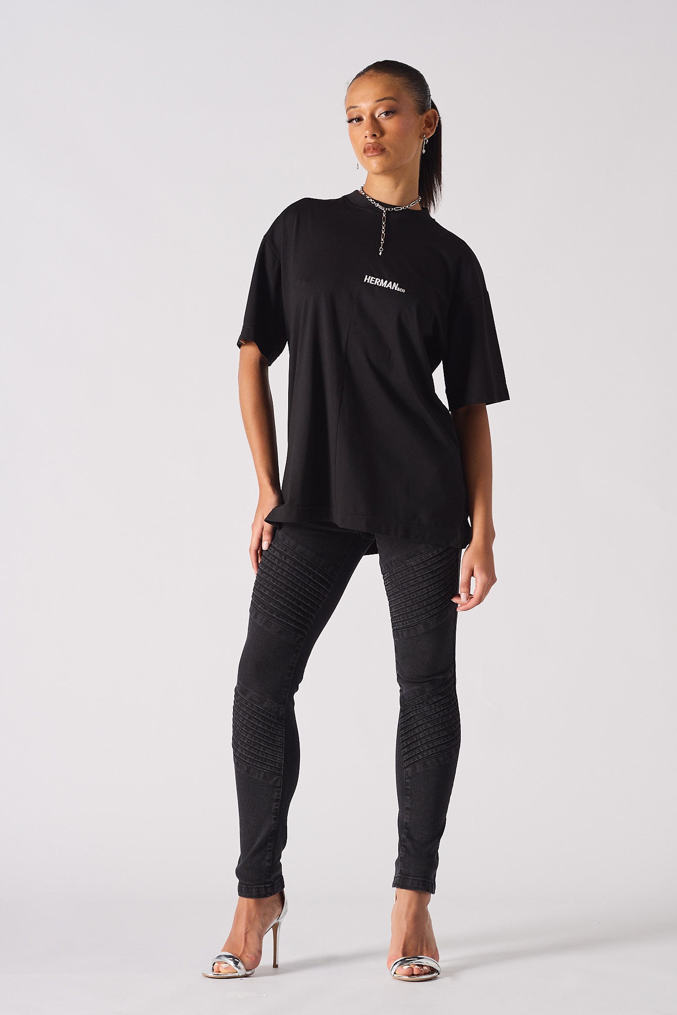 A model styled in the black biker jeans for women with an oversized t-shirt.