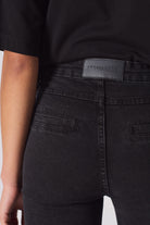 Close-up of the back pocket and logo patch on the women's black biker jeans.