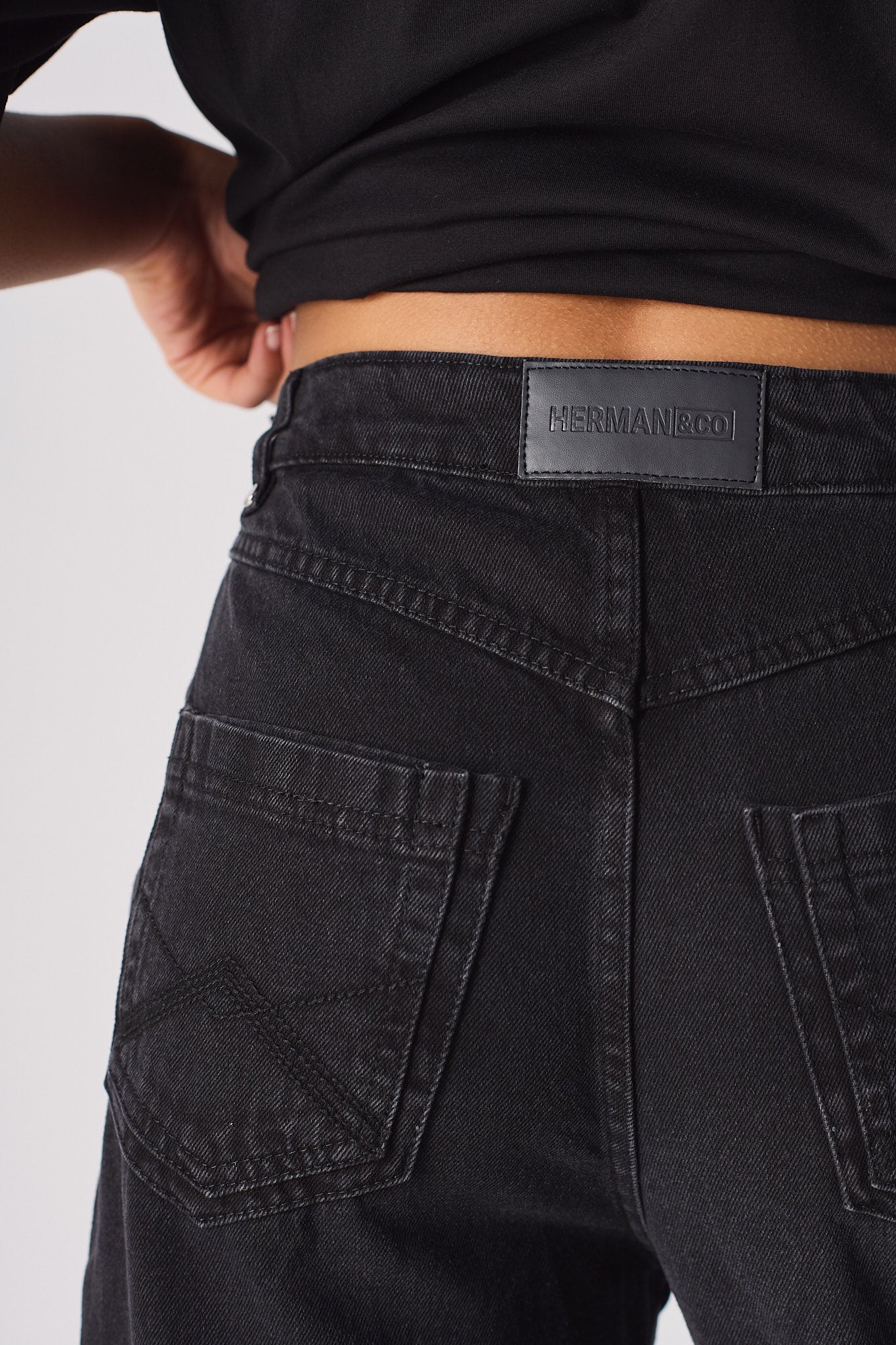 Close-up of the back pocket and logo patch on the women's black cargo jeans.