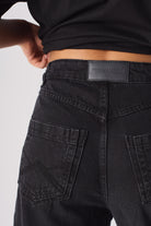 Close-up of the back pocket and logo patch on the women's black cargo jeans.
