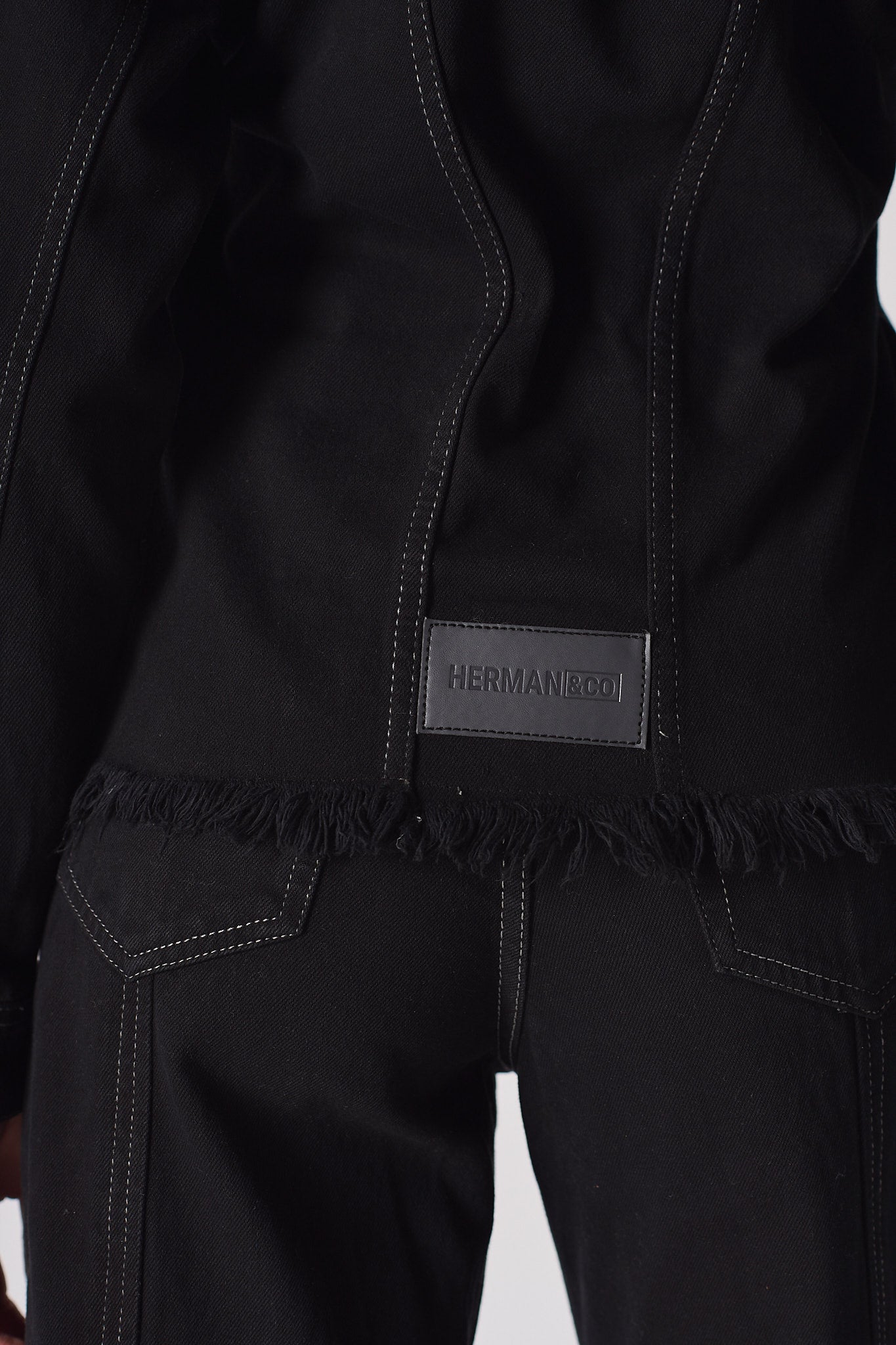 Close-up of the logo patch on the back of the black denim jacket.