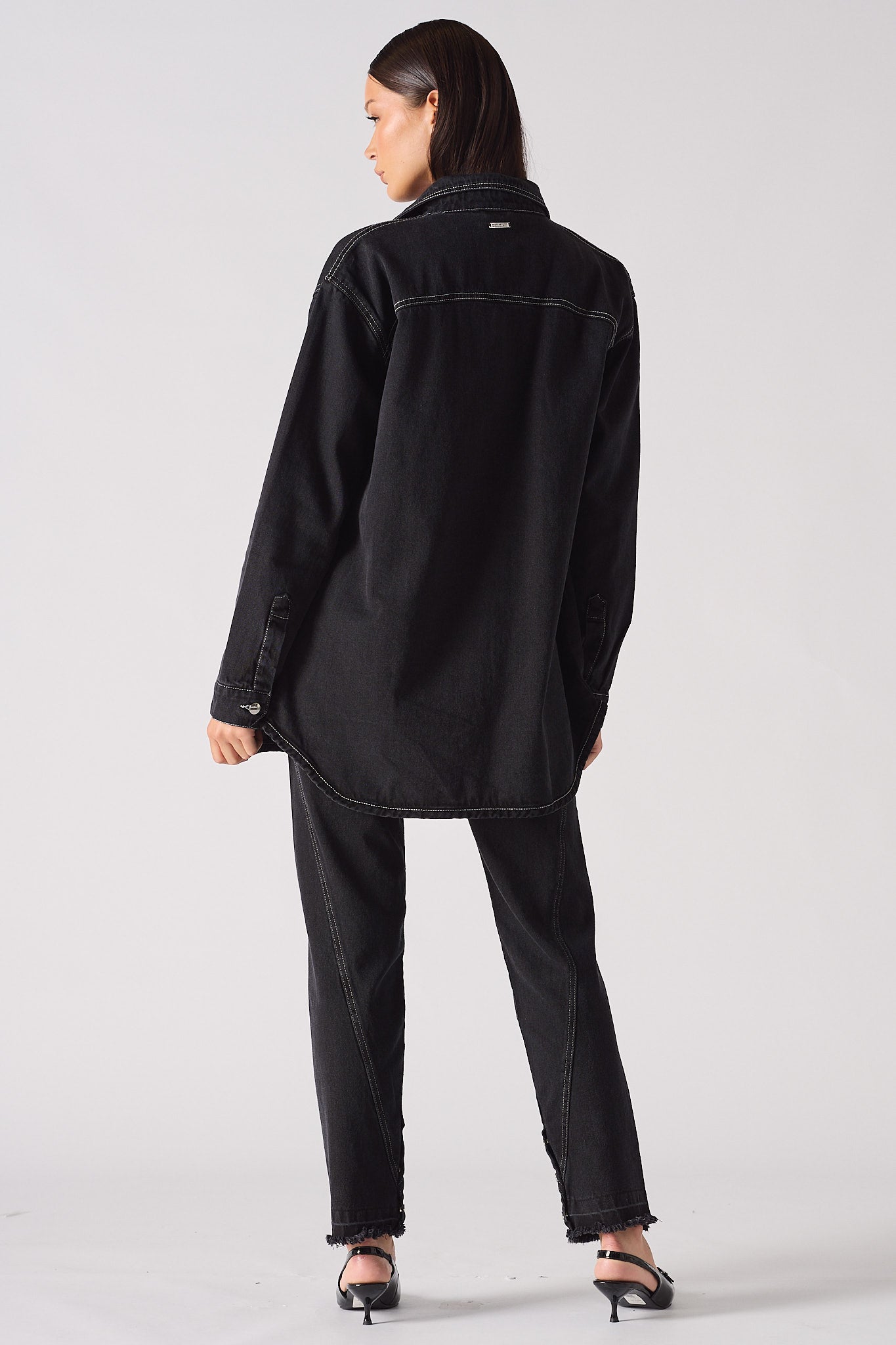 Back view of a model in the black denim oversized shirt for women.