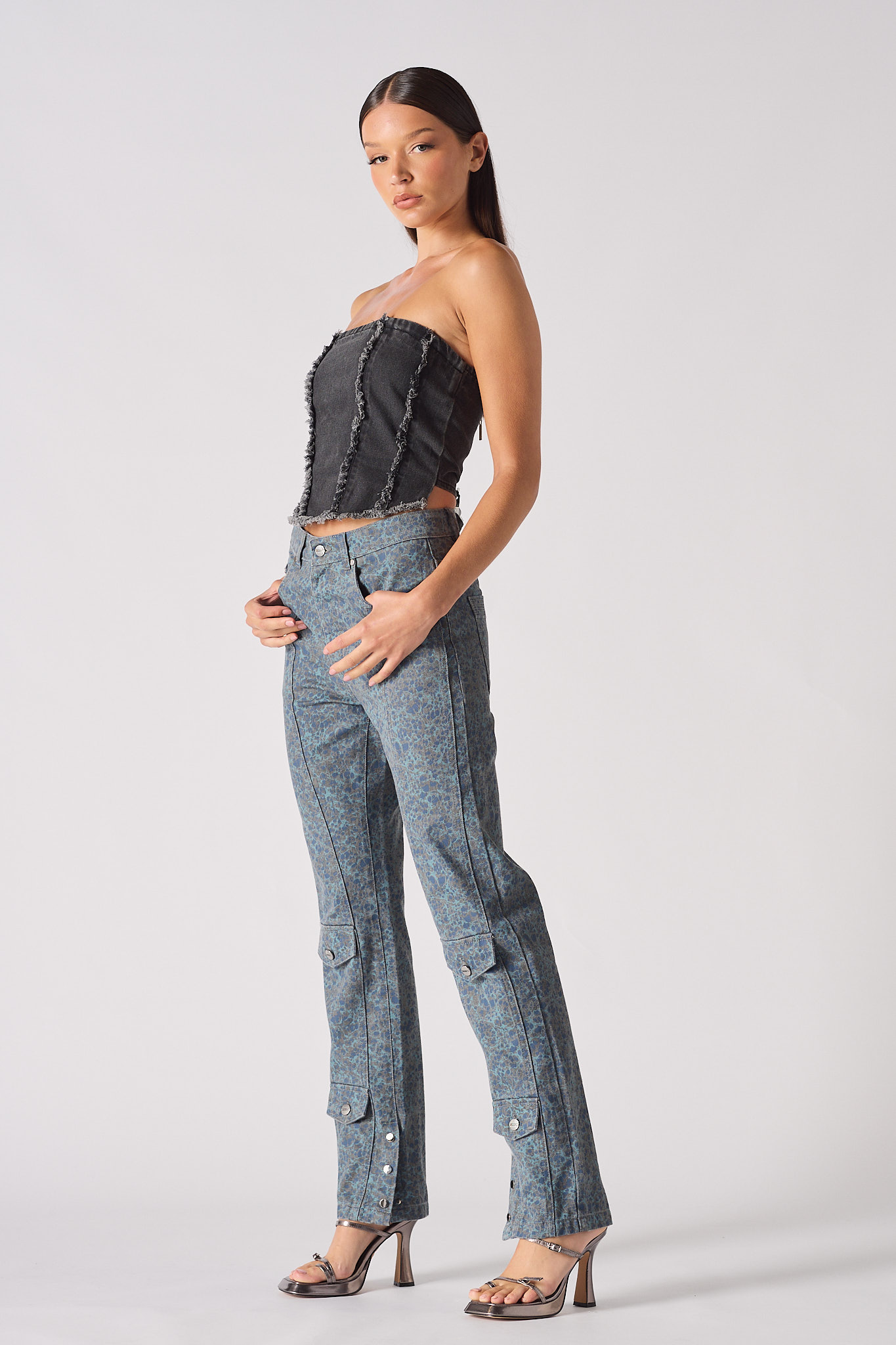 Side view of a model wearing the black distressed denim corset top.